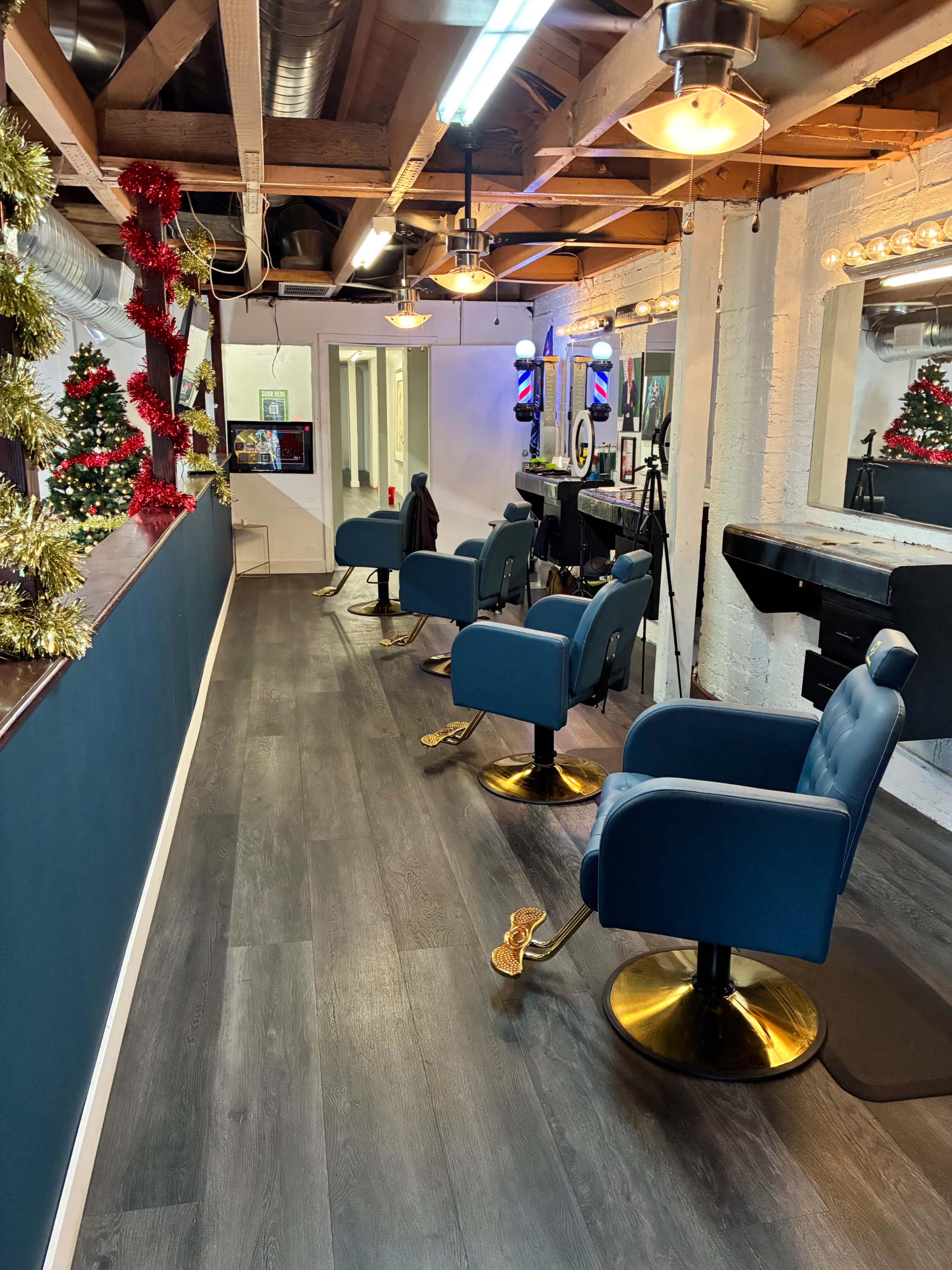 The image shows a modern hair salon interior with teal barber chairs, decorative holiday garlands, and a large mirror along the wall.