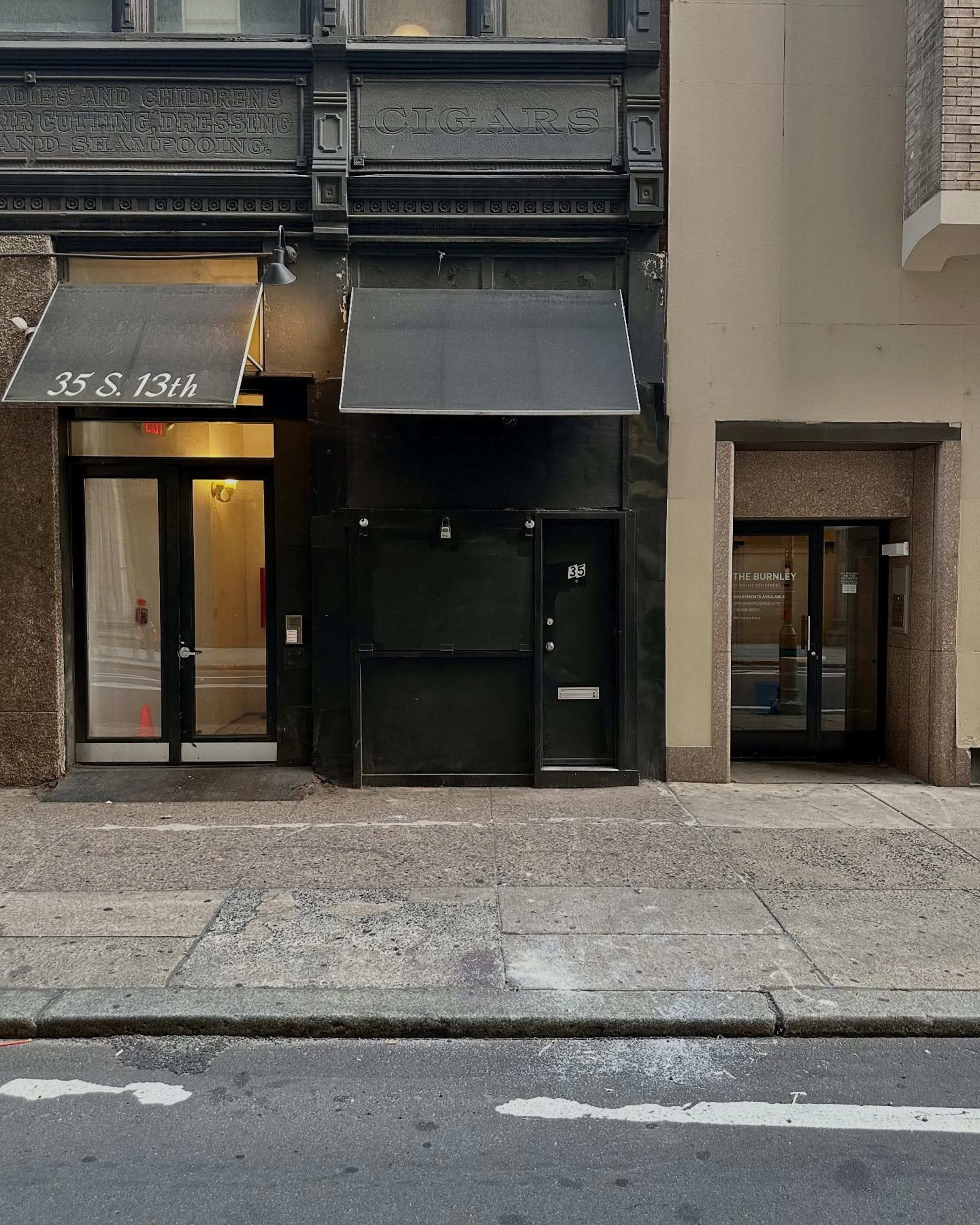 The image shows a street view of two adjacent buildings with distinct entrances, one featuring a black door and awning, and the other with a glass door labeled "THE BENJAMIN."