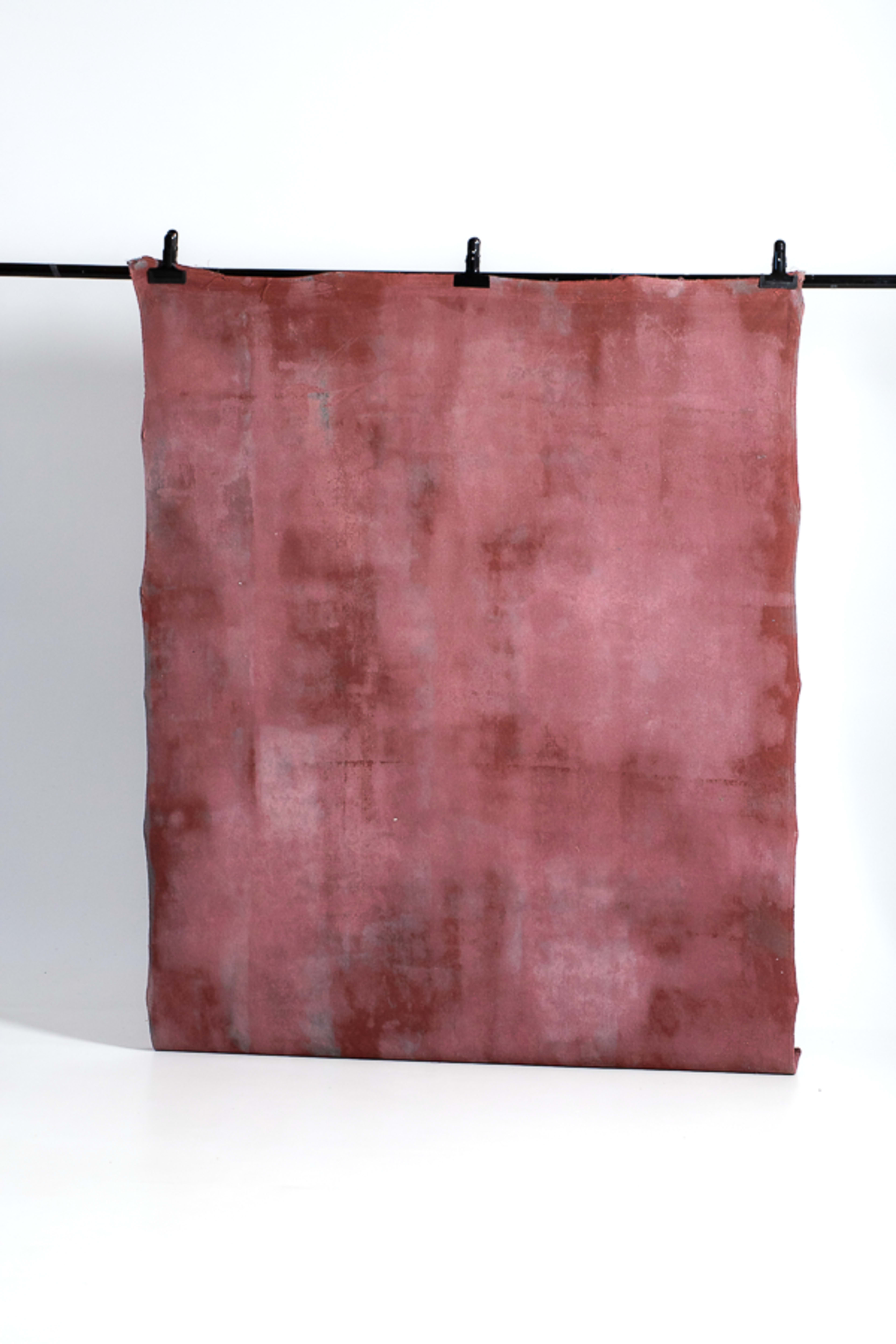 The image shows a large piece of textured fabric hanging from a black rod against a plain white background.