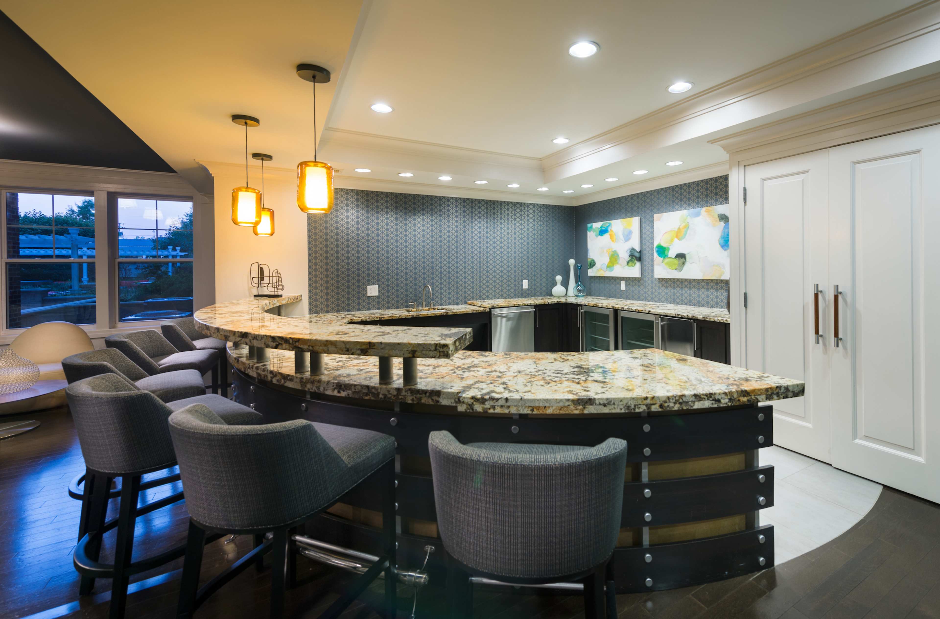 A modern kitchen with a curved granite bar, sleek cabinetry, and pendant lighting above the seating area.