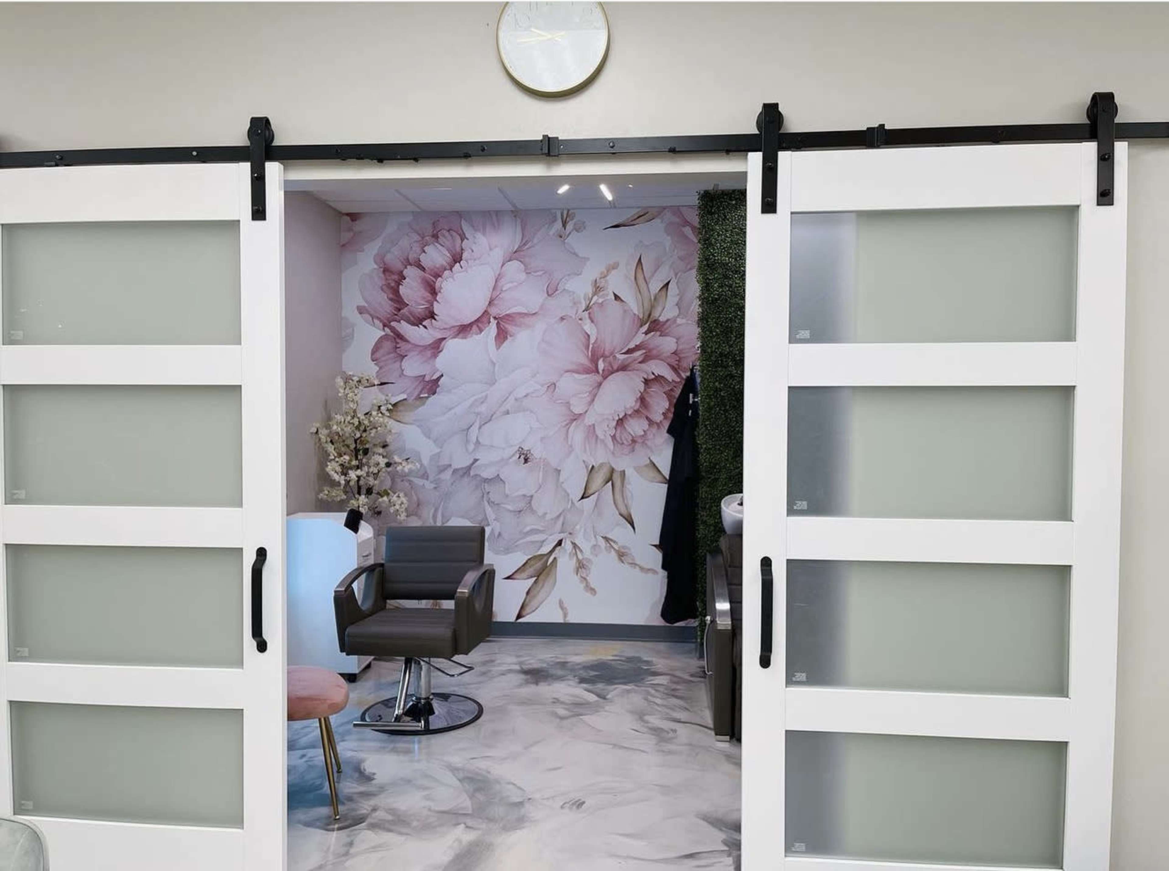 A modern beauty salon interior with sliding glass doors opening to a floral accent wall and contemporary furniture.