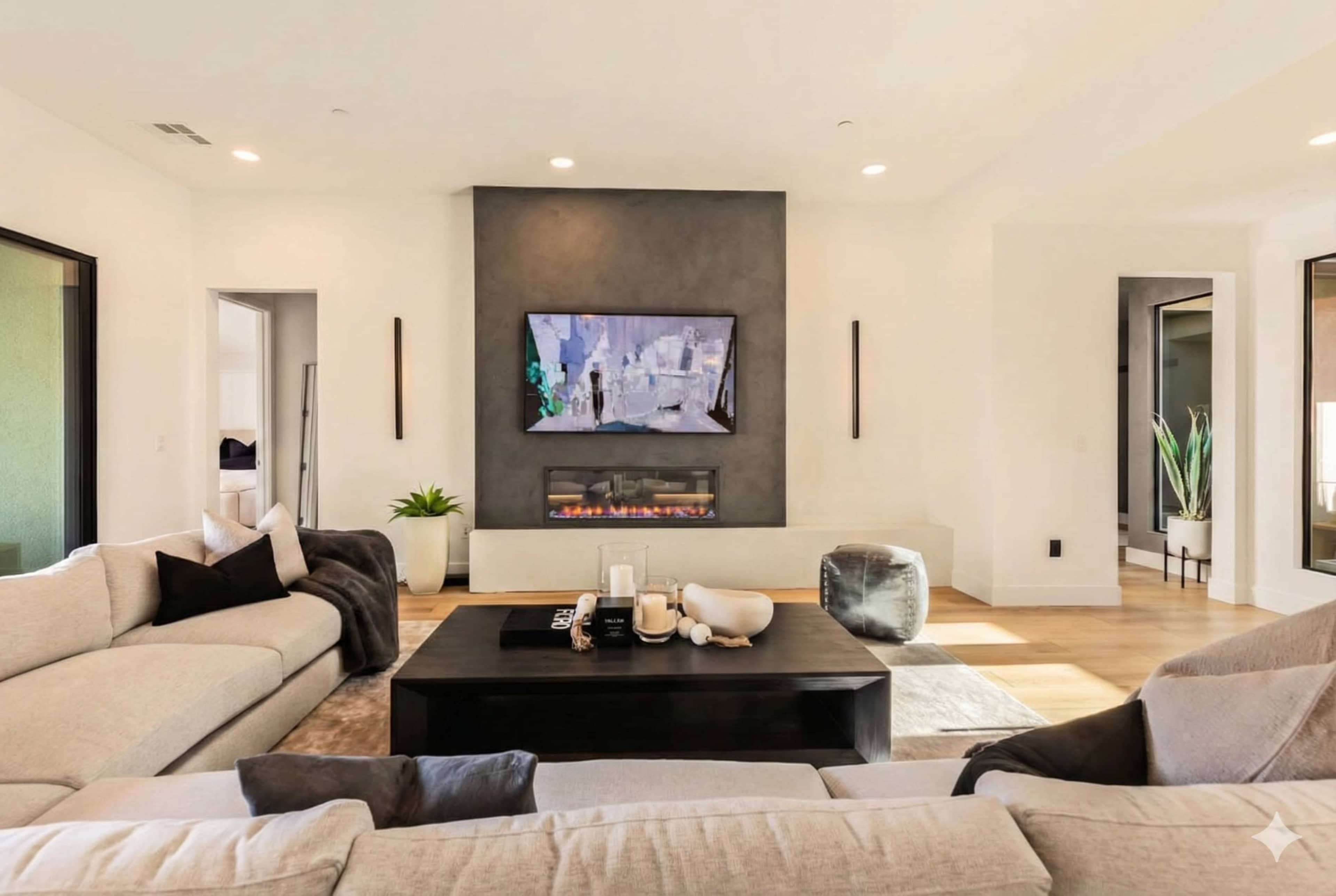 A modern living room features a large sectional sofa, a coffee table, and a wall-mounted television above an electric fireplace.