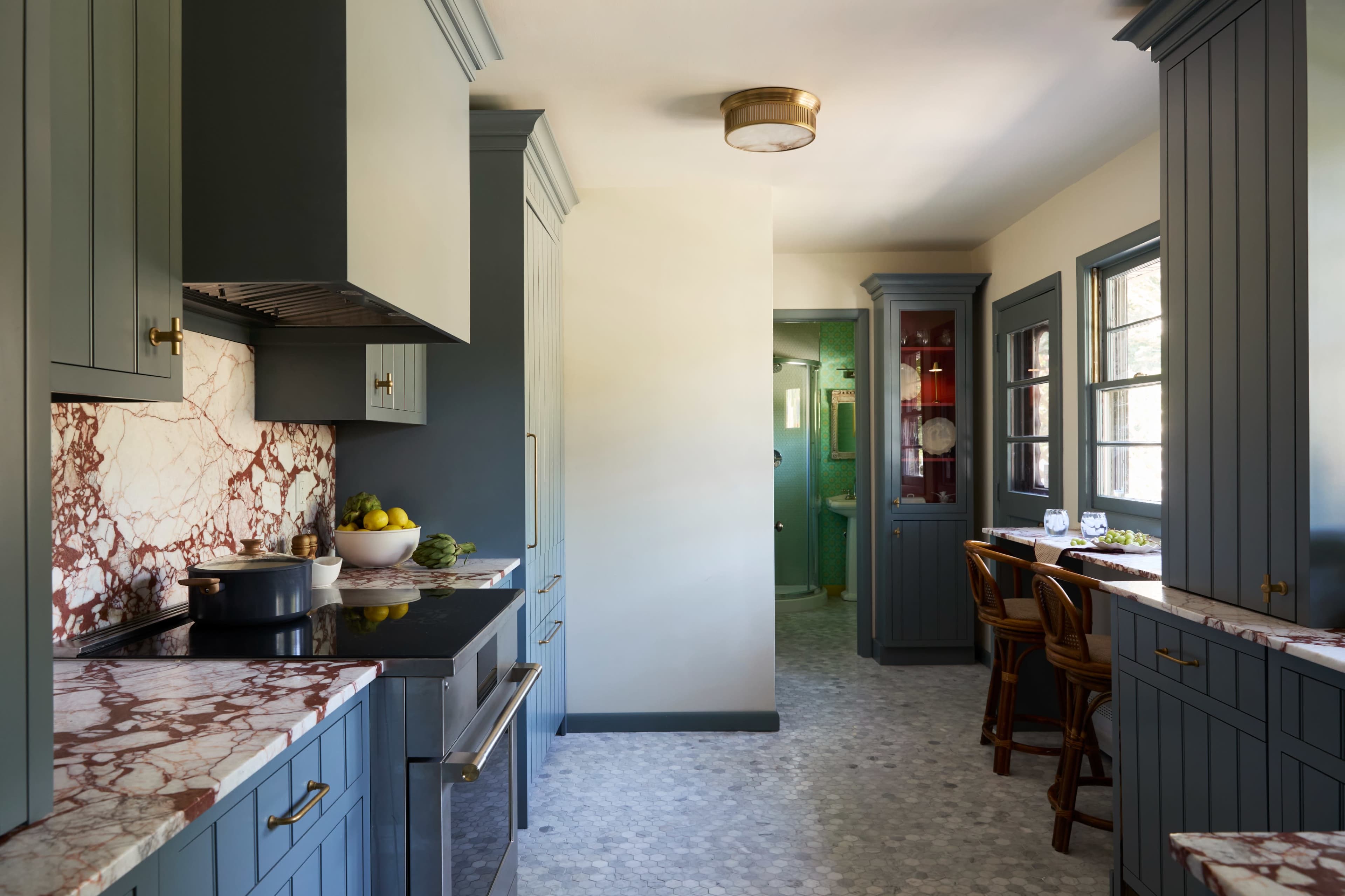 The kitchen features blue cabinetry, marble countertops, and a dining area with wooden chairs.