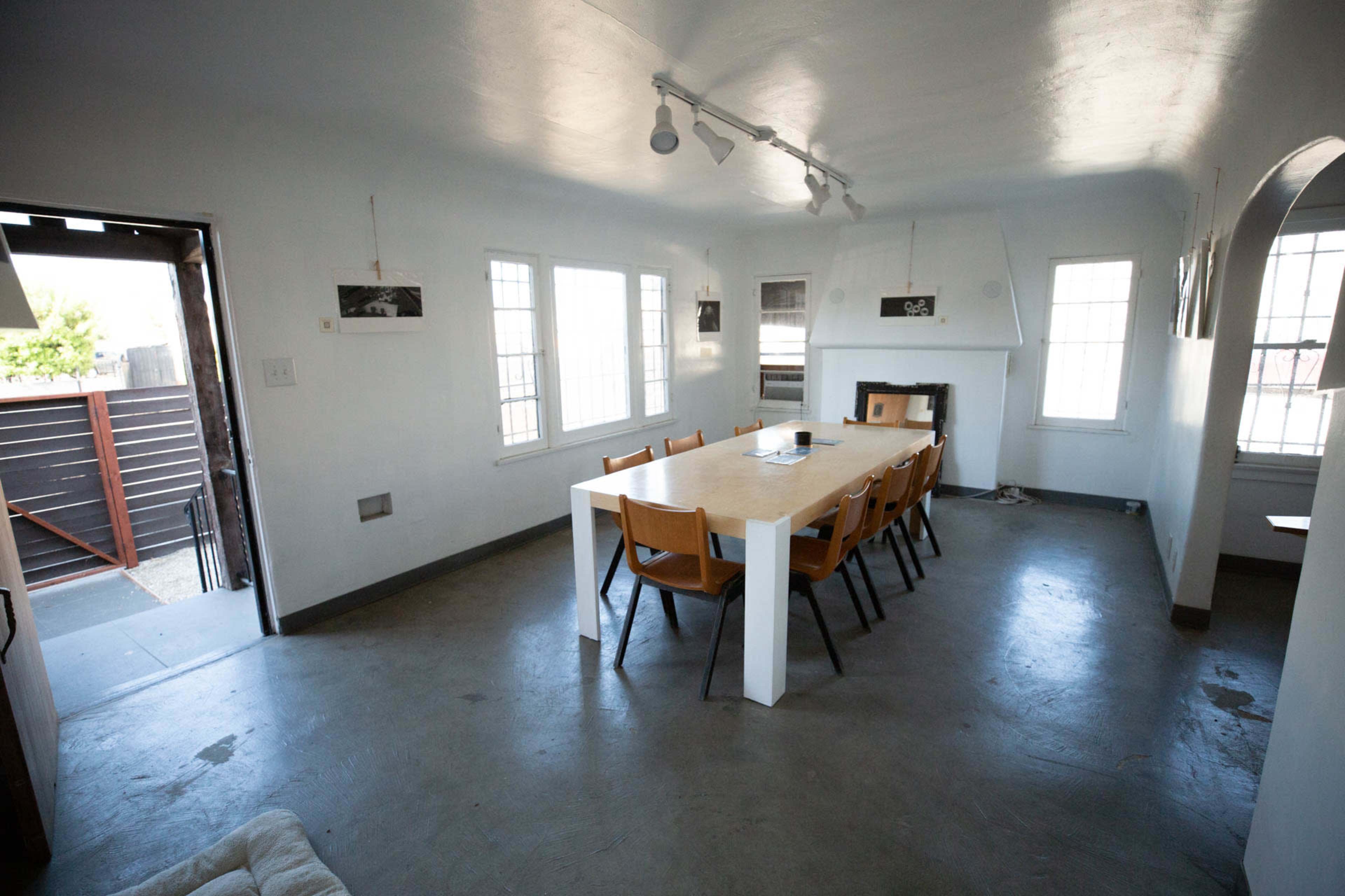 A spacious dining area features a long table with eight chairs, surrounded by windows that let in natural light.