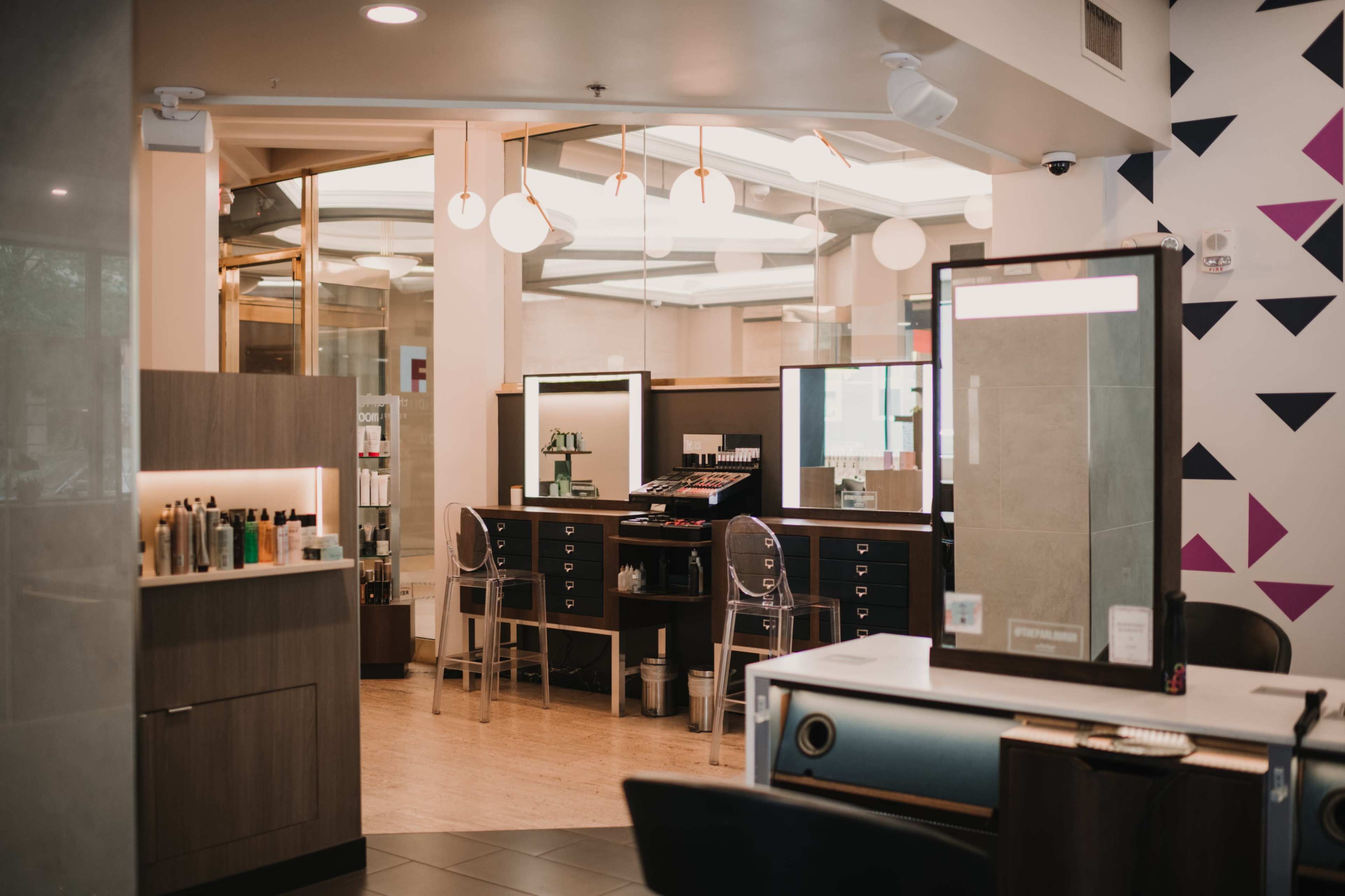 A modern salon interior featuring styling stations, mirrors, and product displays.