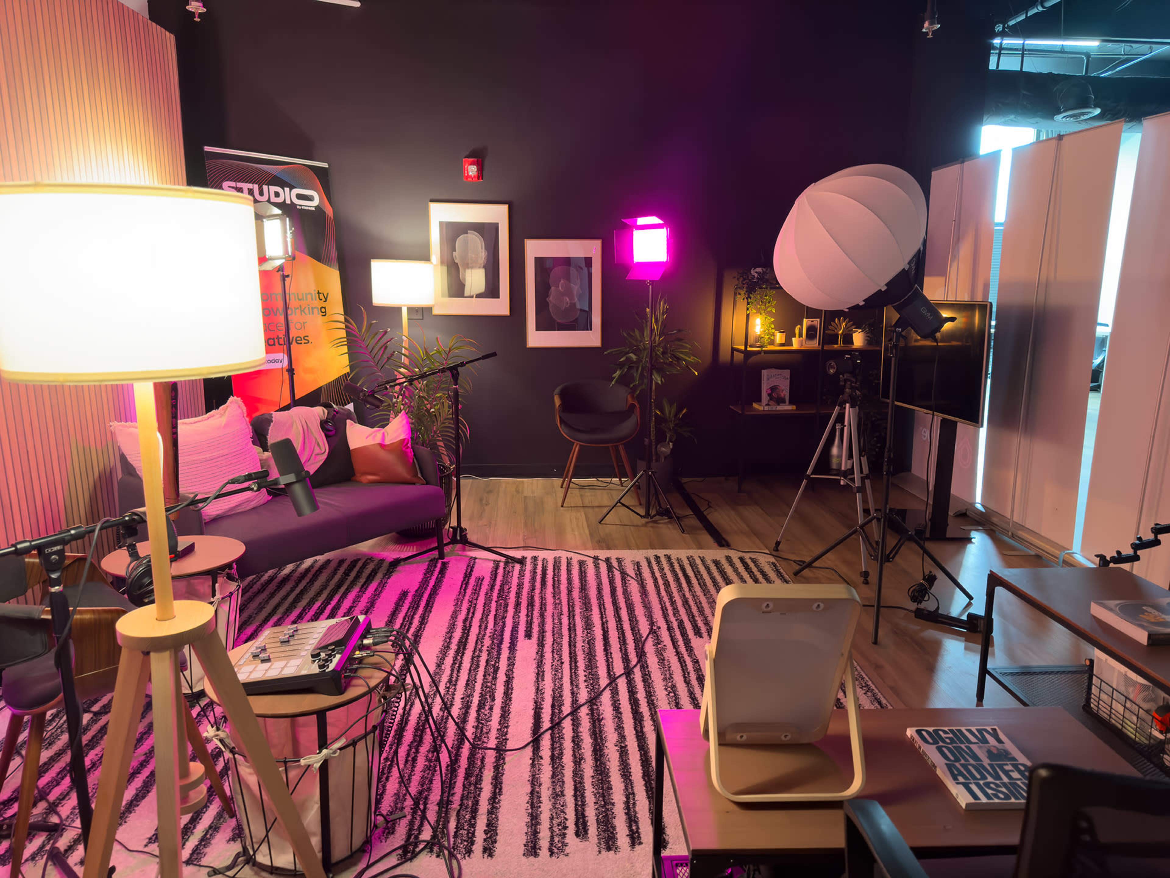 A modern studio setup with seating, lights, and photography equipment arranged for a video or photo shoot.