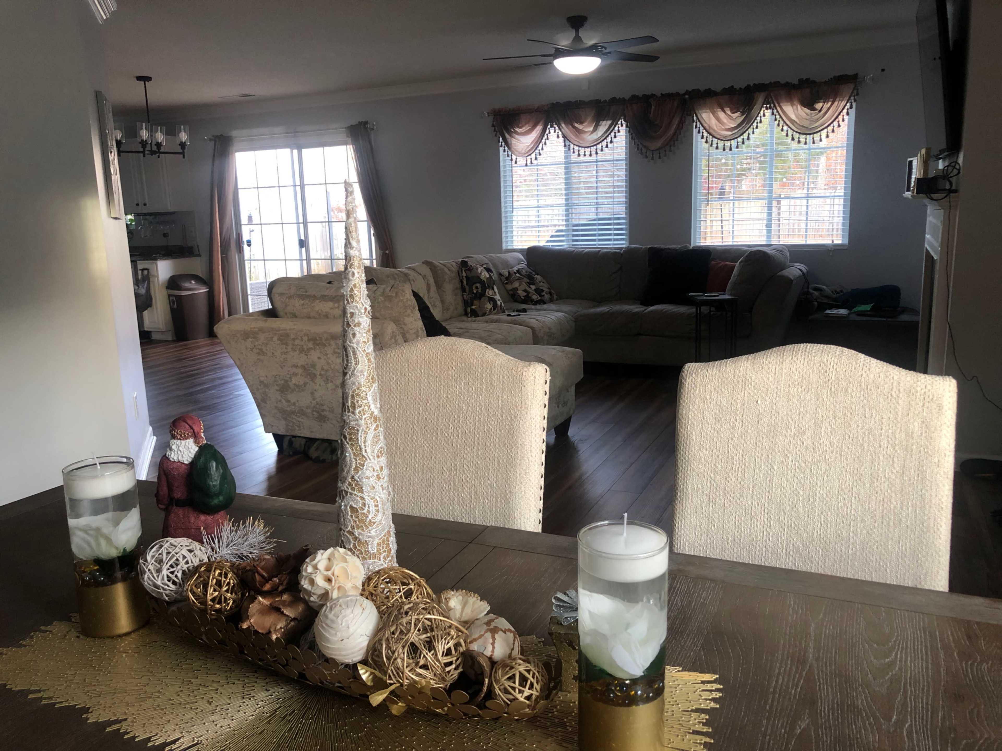 A living area with a decorated dining table in the foreground and a sectional sofa in the background.
