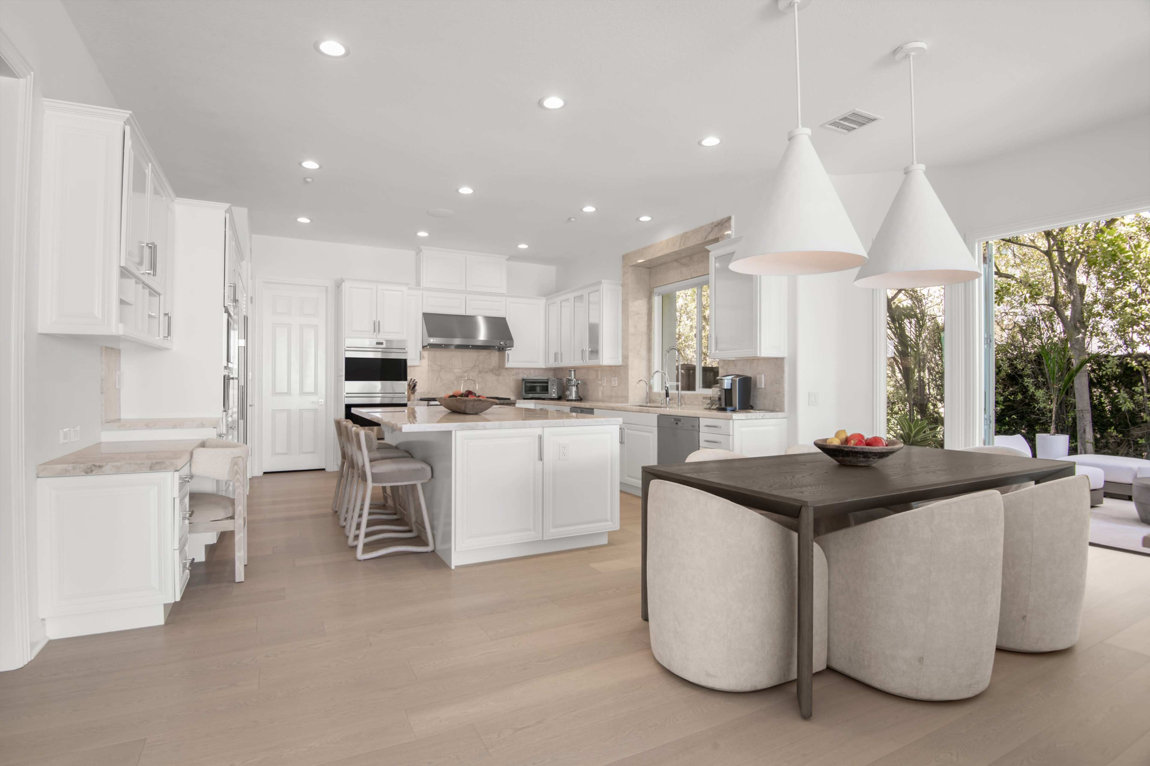 A modern kitchen features white cabinetry, stainless steel appliances, and a seating area with a round table and upholstered chairs.