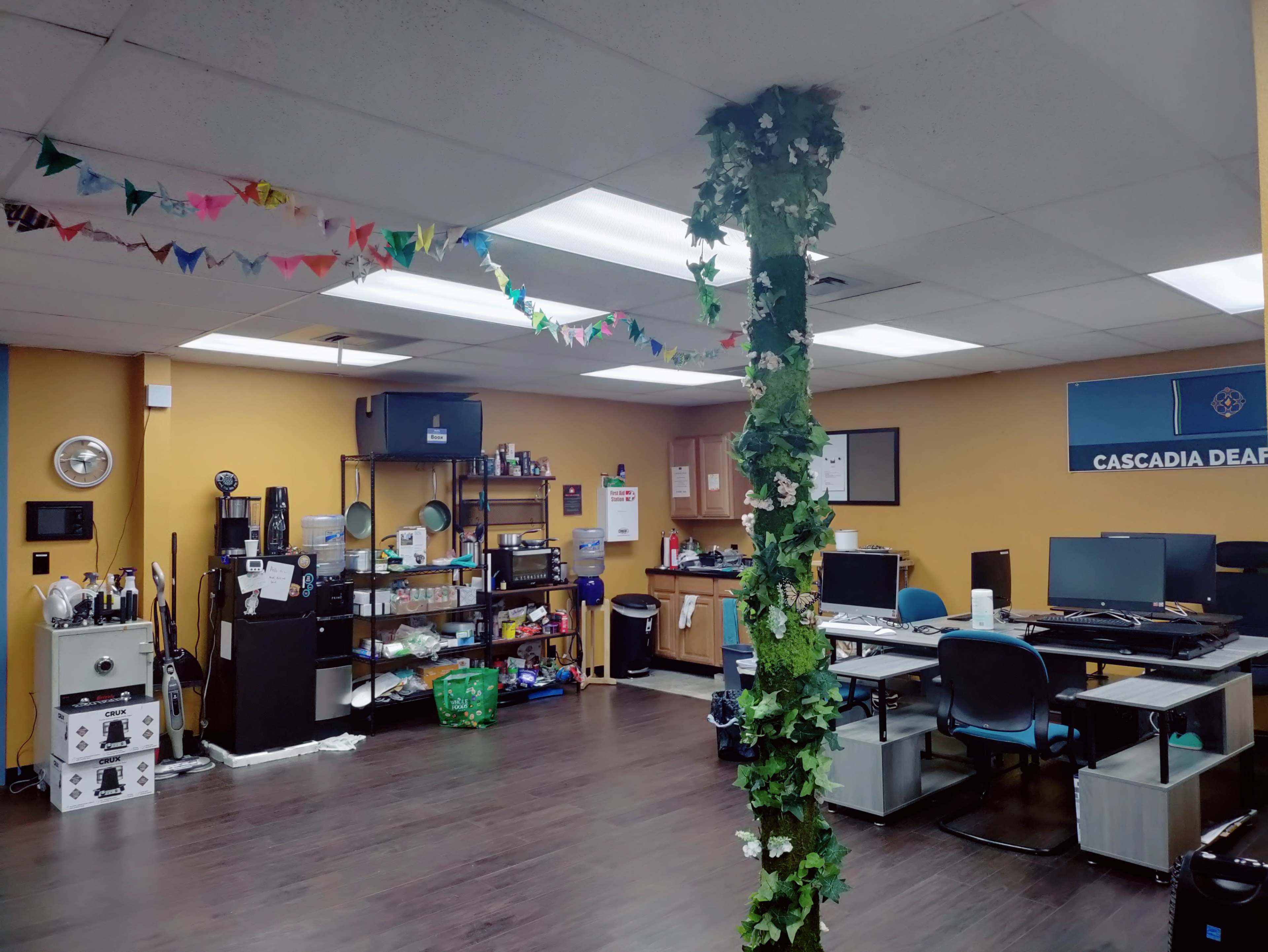 An office space with workstations, storage shelves, and decorative garlands along the ceiling.
