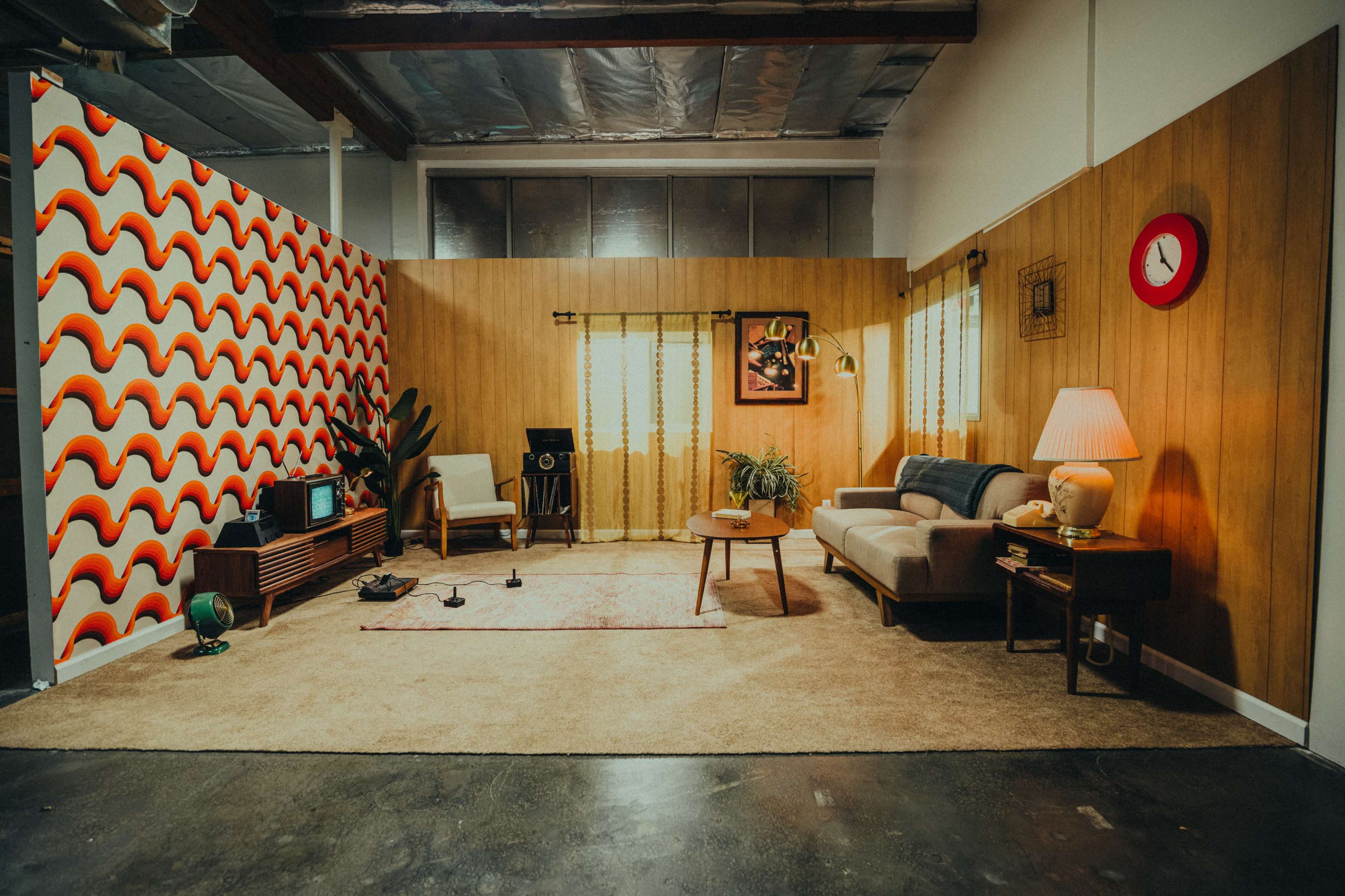 A retro-inspired living room with a patterned wall, a sofa, a coffee table, and various decorative elements.