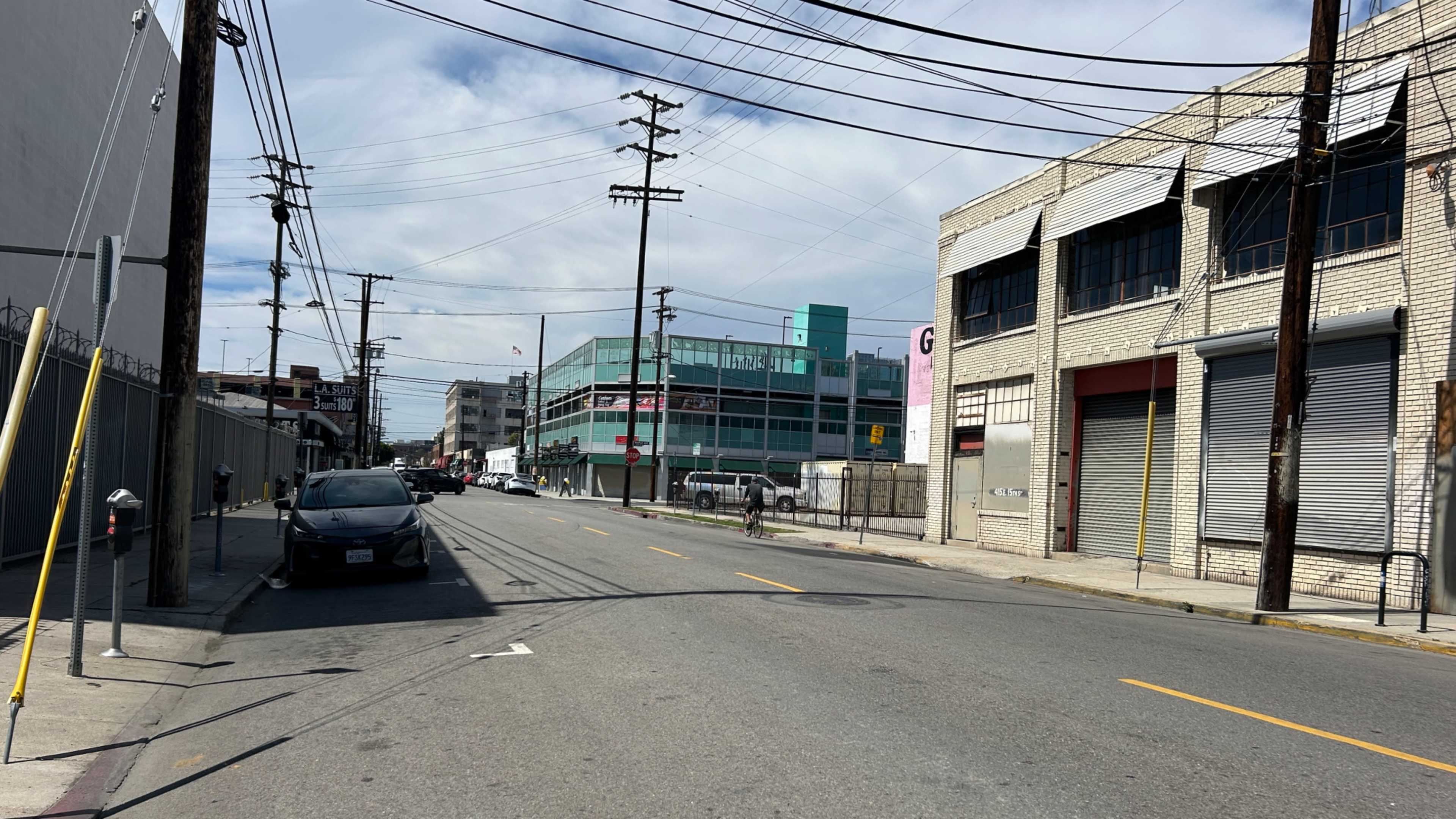 A wide street runs through an industrial area, lined with power poles and buildings on either side.