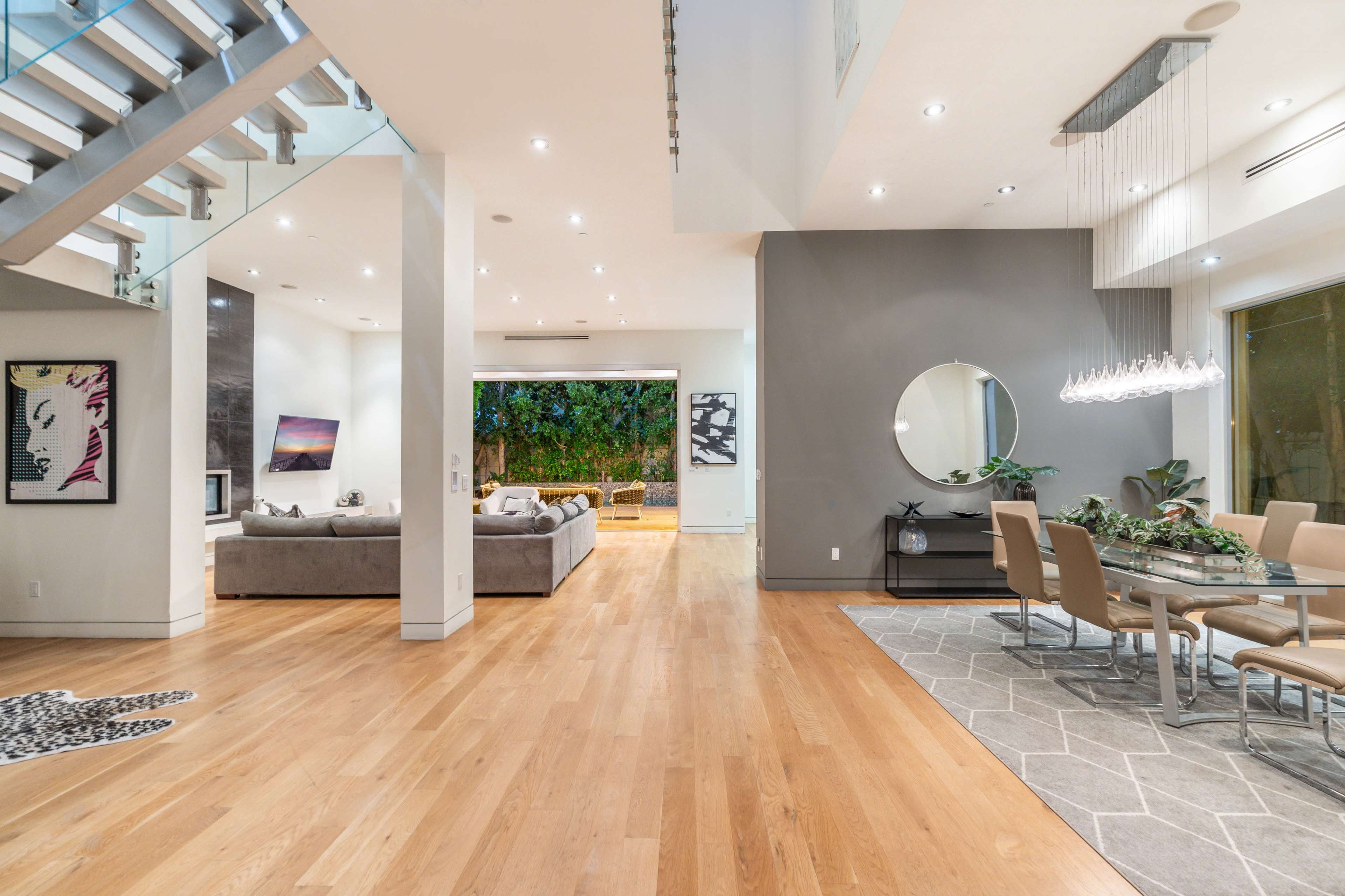 A modern open-concept living space featuring a dining area with a large table and a lounge area with a gray sectional sofa.