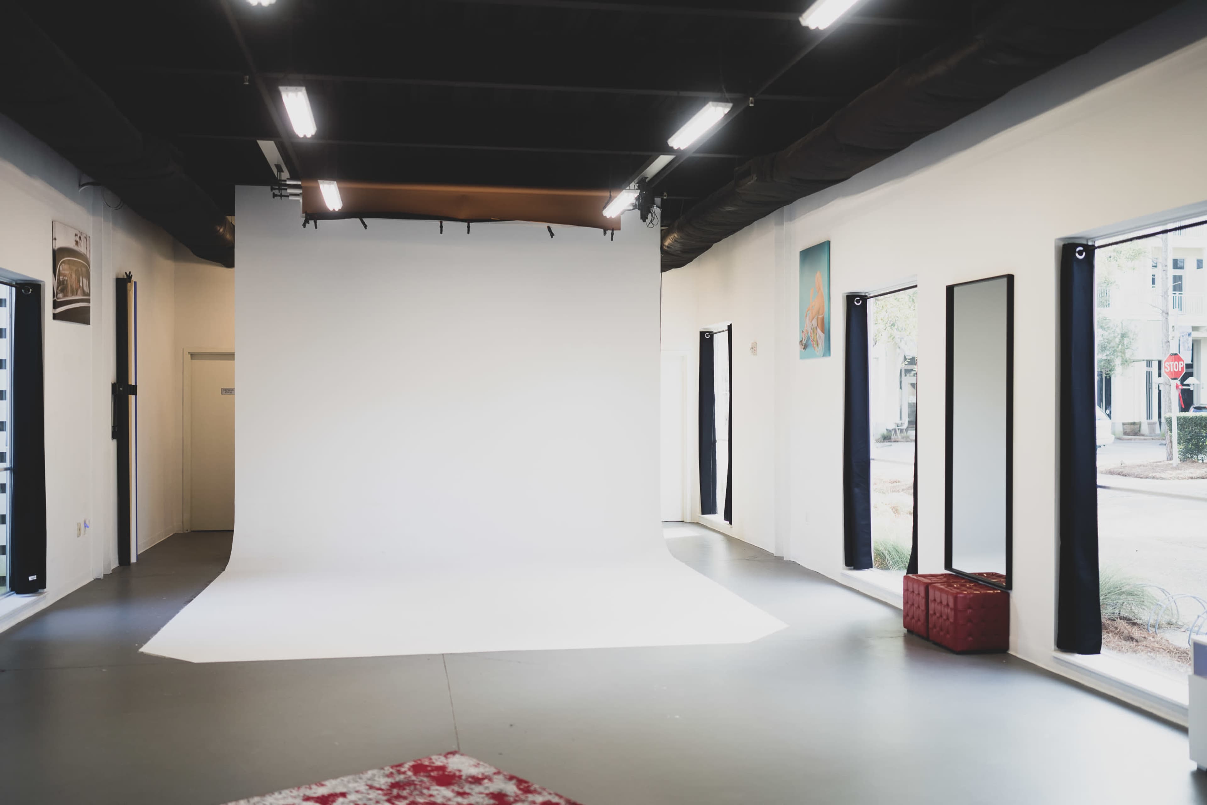 A photography studio featuring a large white backdrop, mirrors, and bright lighting.