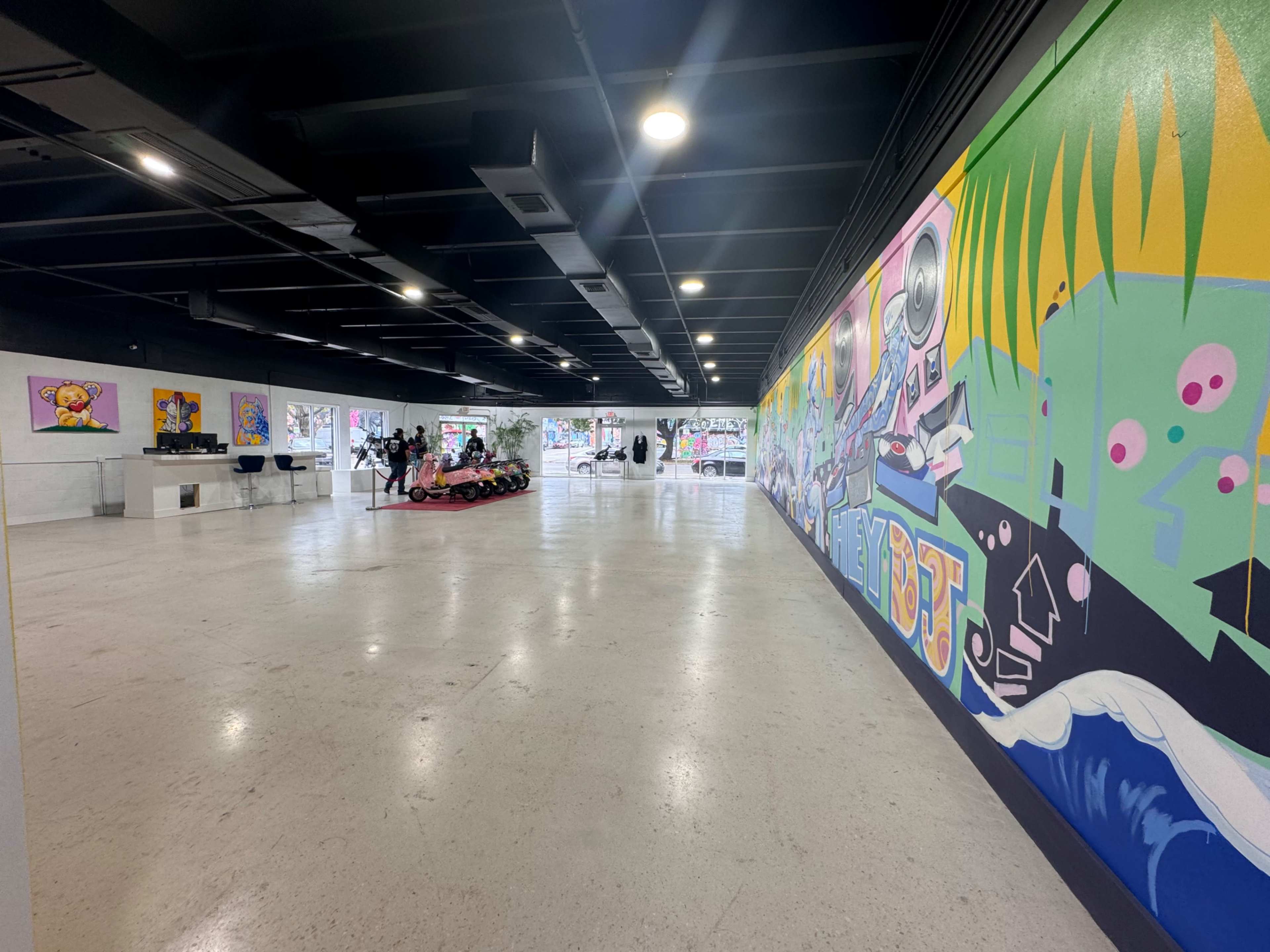 A spacious interior with colorful murals on the walls and several art pieces displayed in an open gallery-like environment.