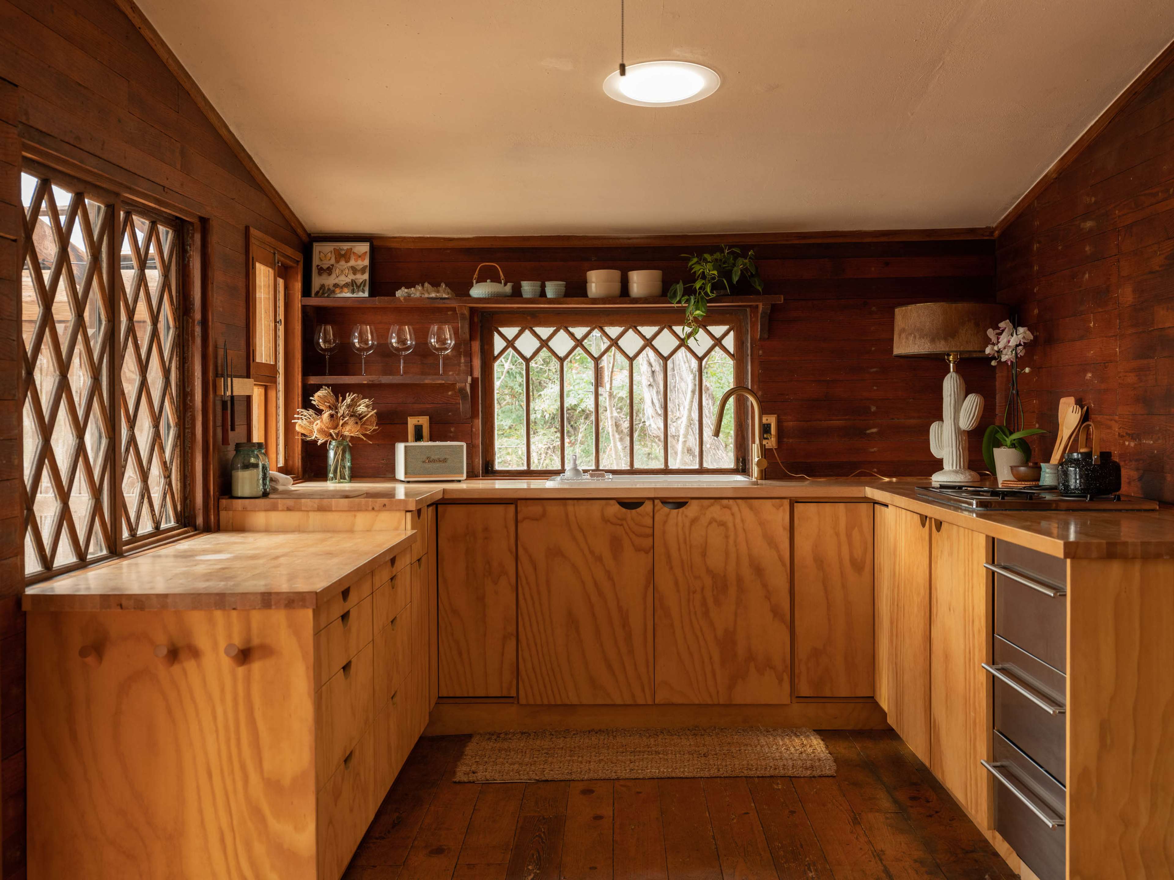The kitchen features wooden cabinetry, a sink under a window, and natural light illuminating the space.