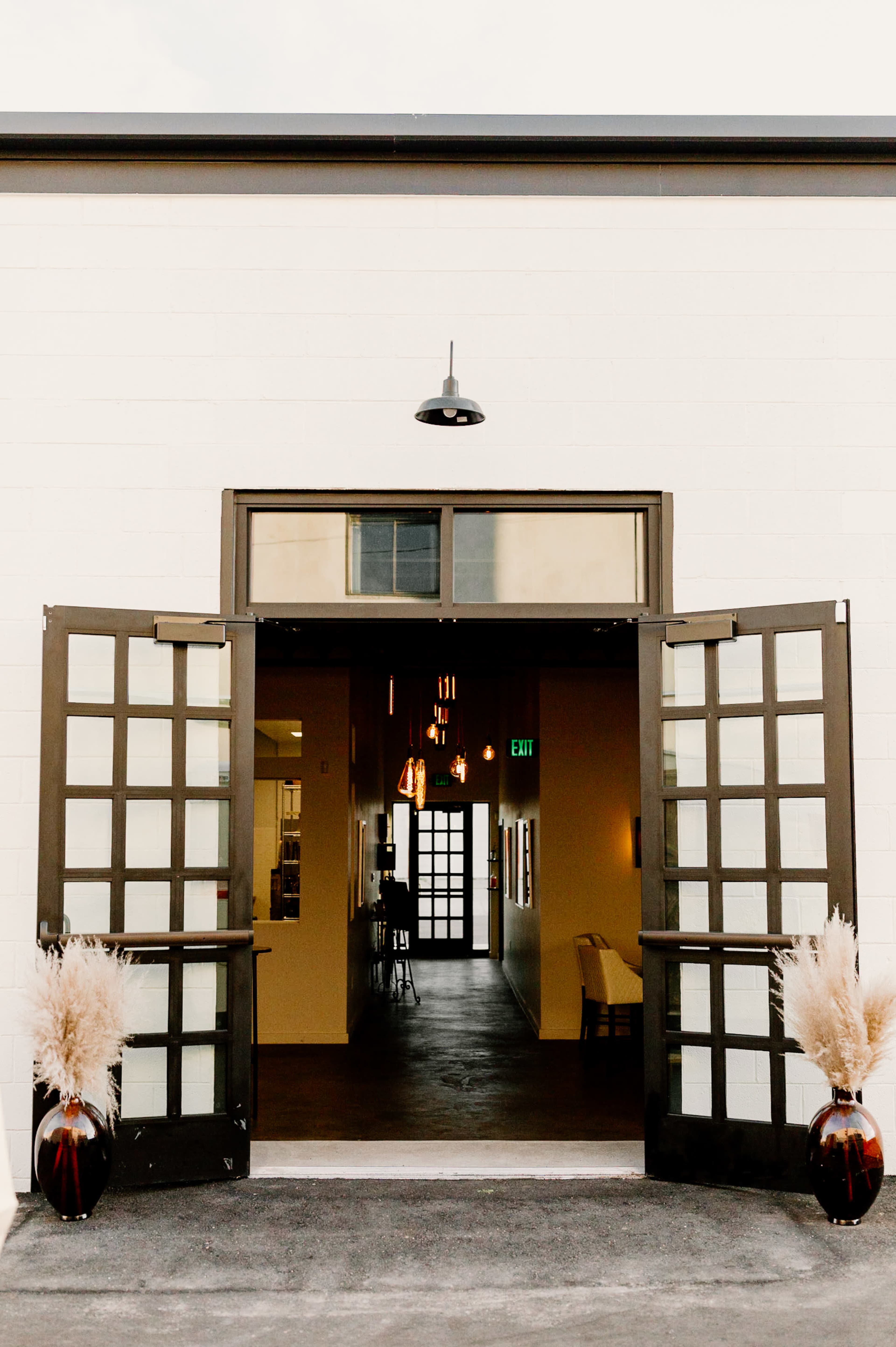A wide entryway with double doors opens to a spacious interior featuring a long hallway illuminated by pendant lights.