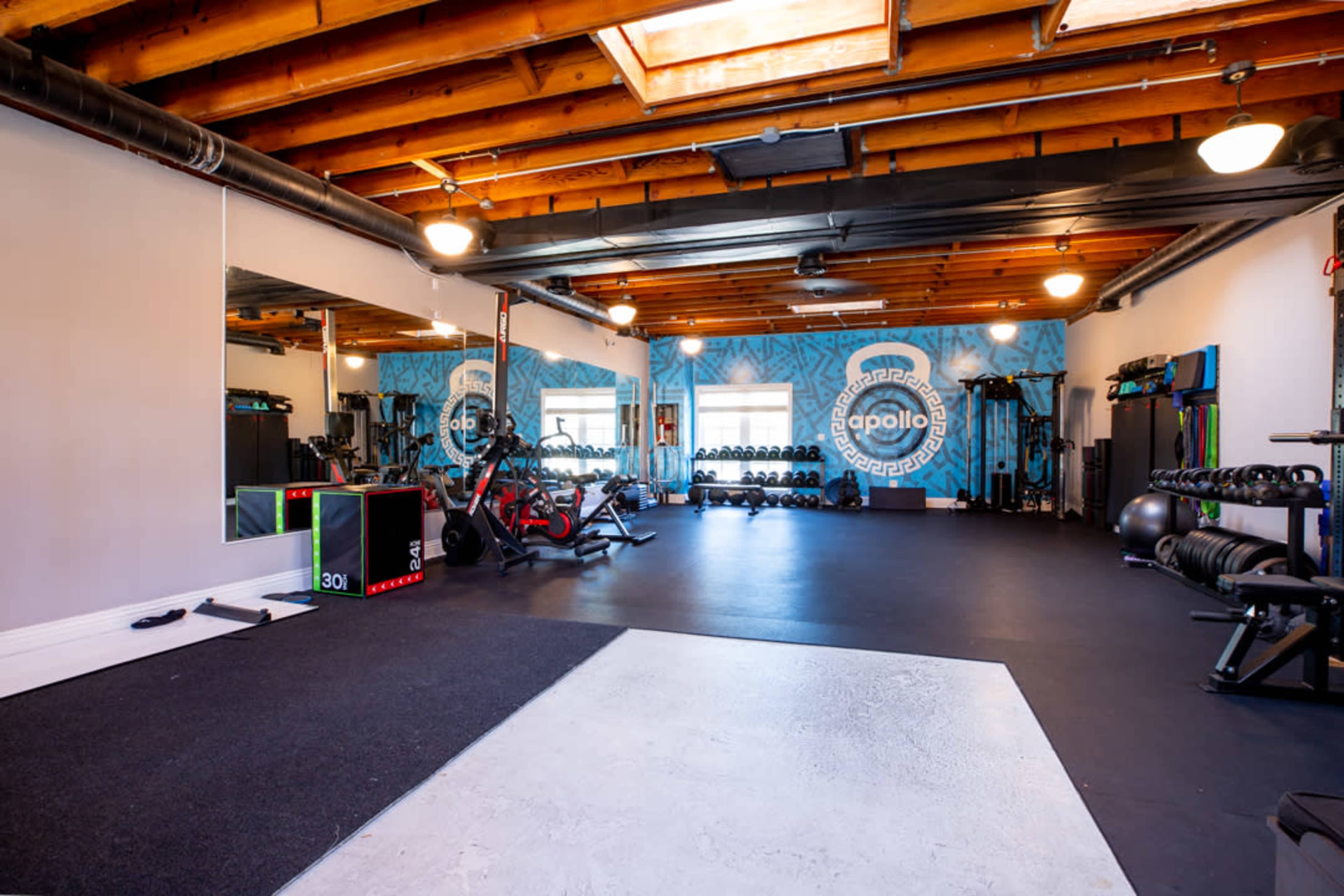 A spacious gym with exercise equipment, including bikes and weights, and large mirrors on one wall.