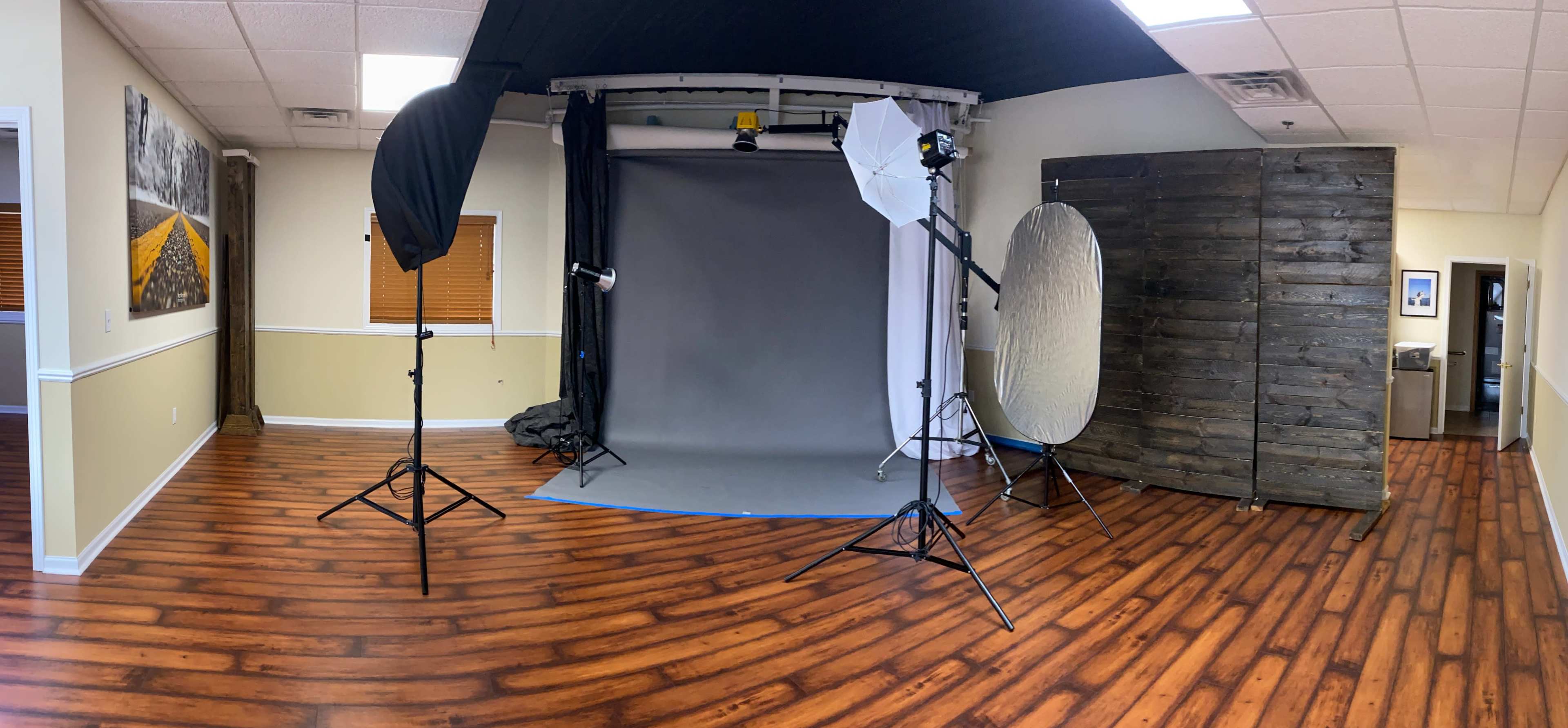 A photography studio with a backdrop, lighting equipment, and wooden walls.