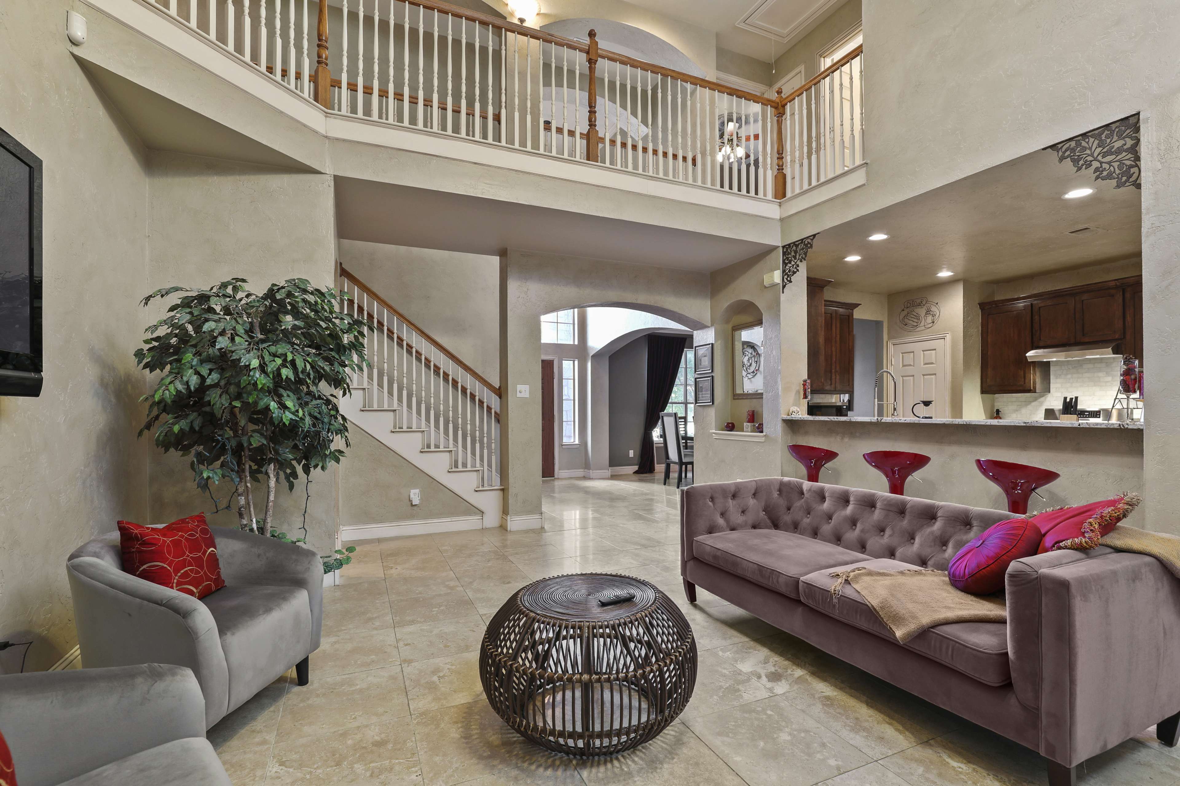 A spacious living area with a staircase, a modern couch, and a dining space visible in the background.