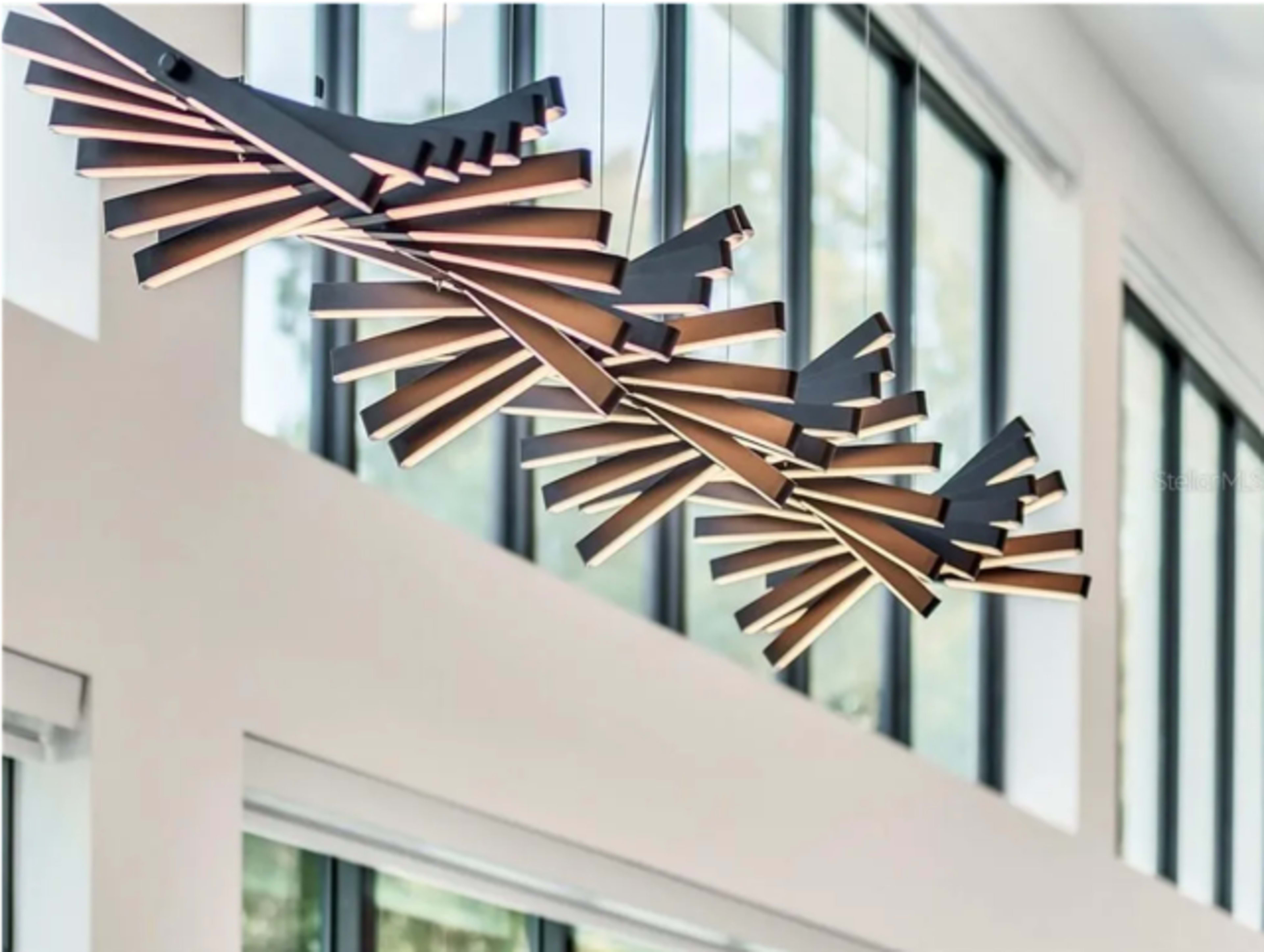 The image features modern pendant lights with a geometric design, suspended from a ceiling in a space with large windows.