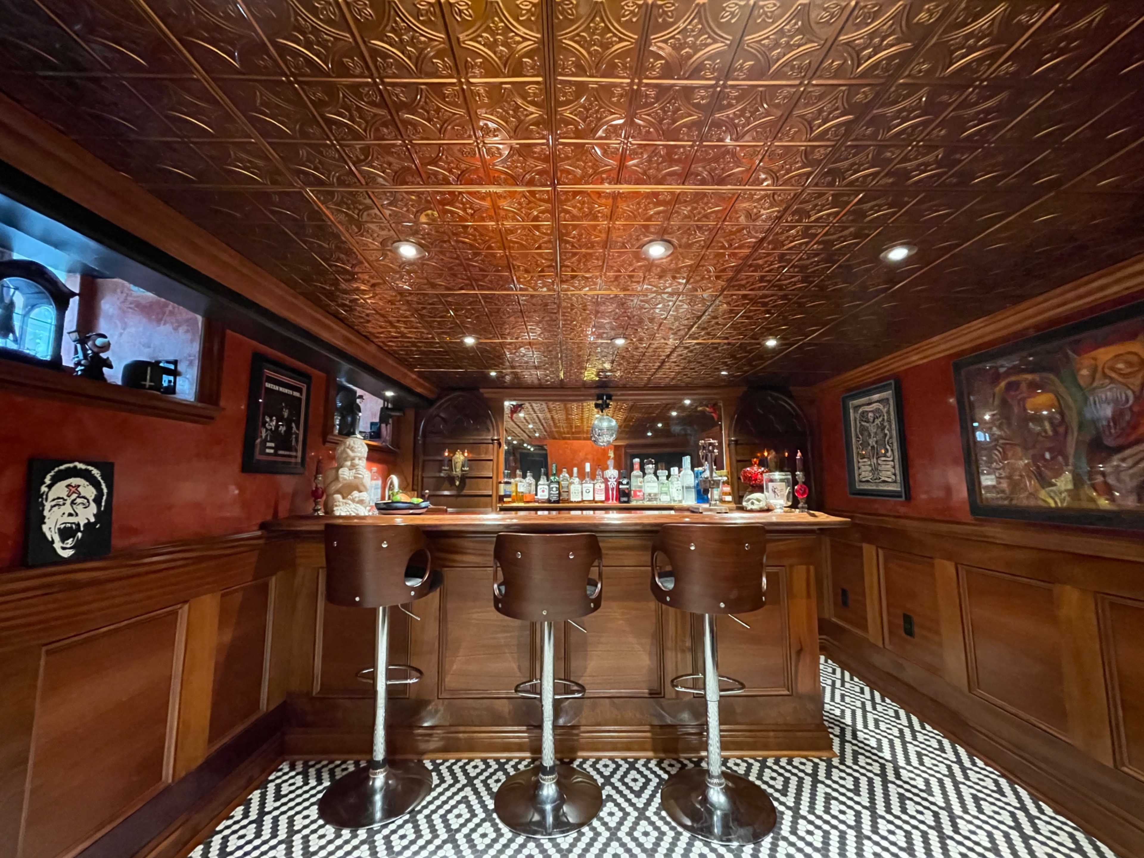 The image shows a vintage-style bar area with three stools, a patterned floor, and a ceiling featuring an ornate design.