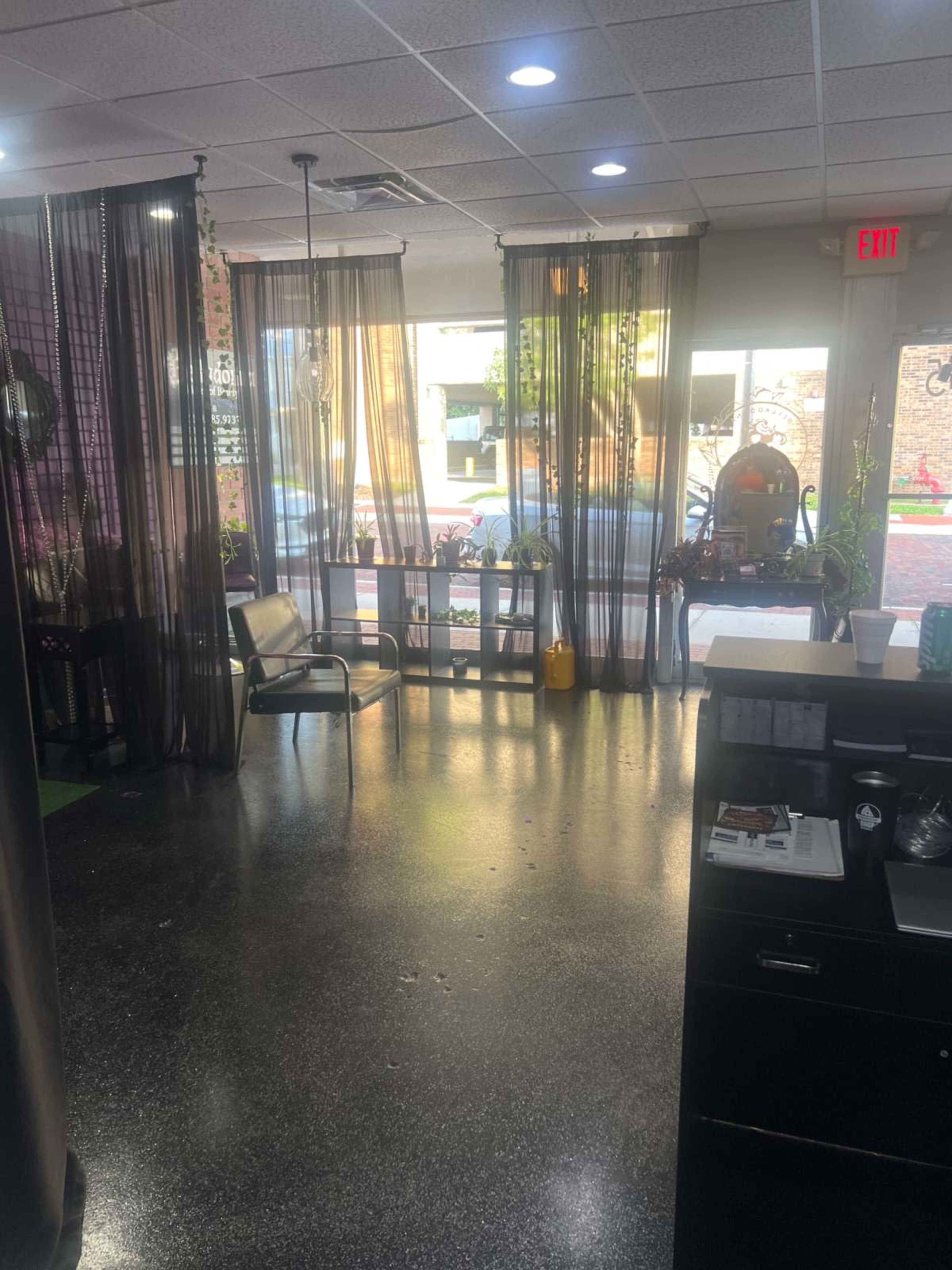 The image shows a salon interior with sheer curtains dividing the space, a chair on one side, and natural light streaming in through the front windows.