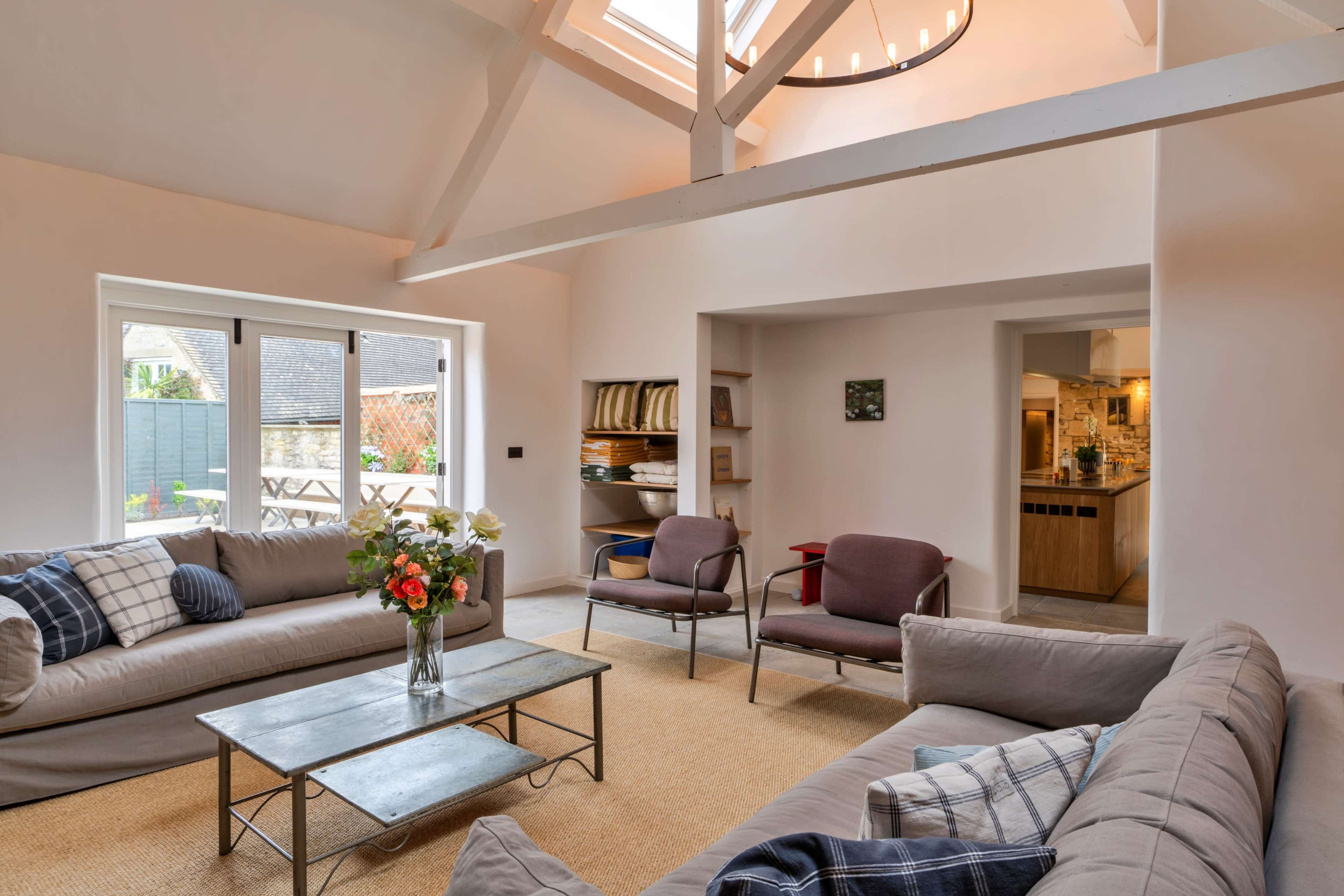 A modern living room with two sofas, a coffee table, and large windows that open to a garden area.