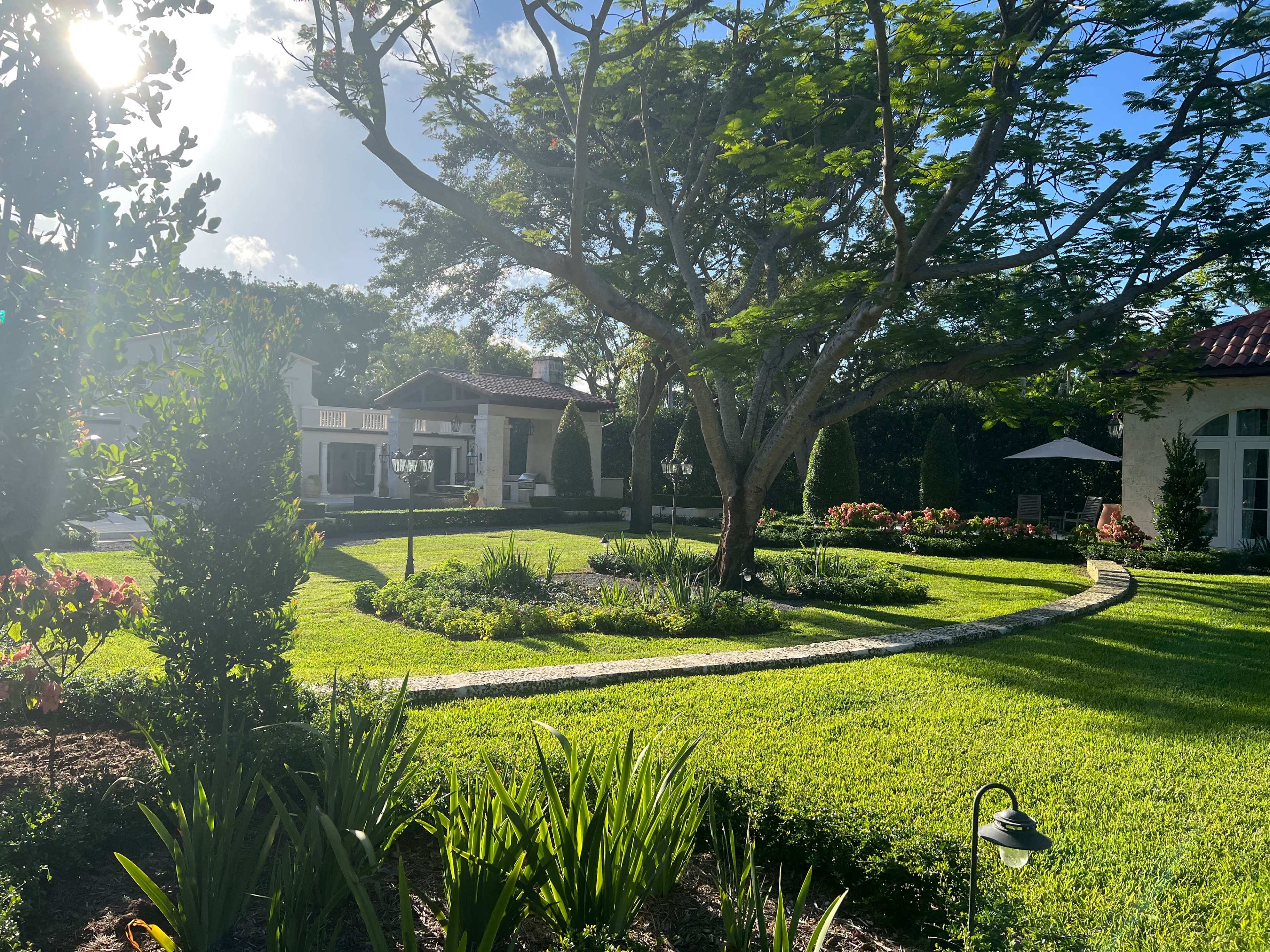 A landscaped garden features a curved stone path surrounded by lush greenery and flowering plants.