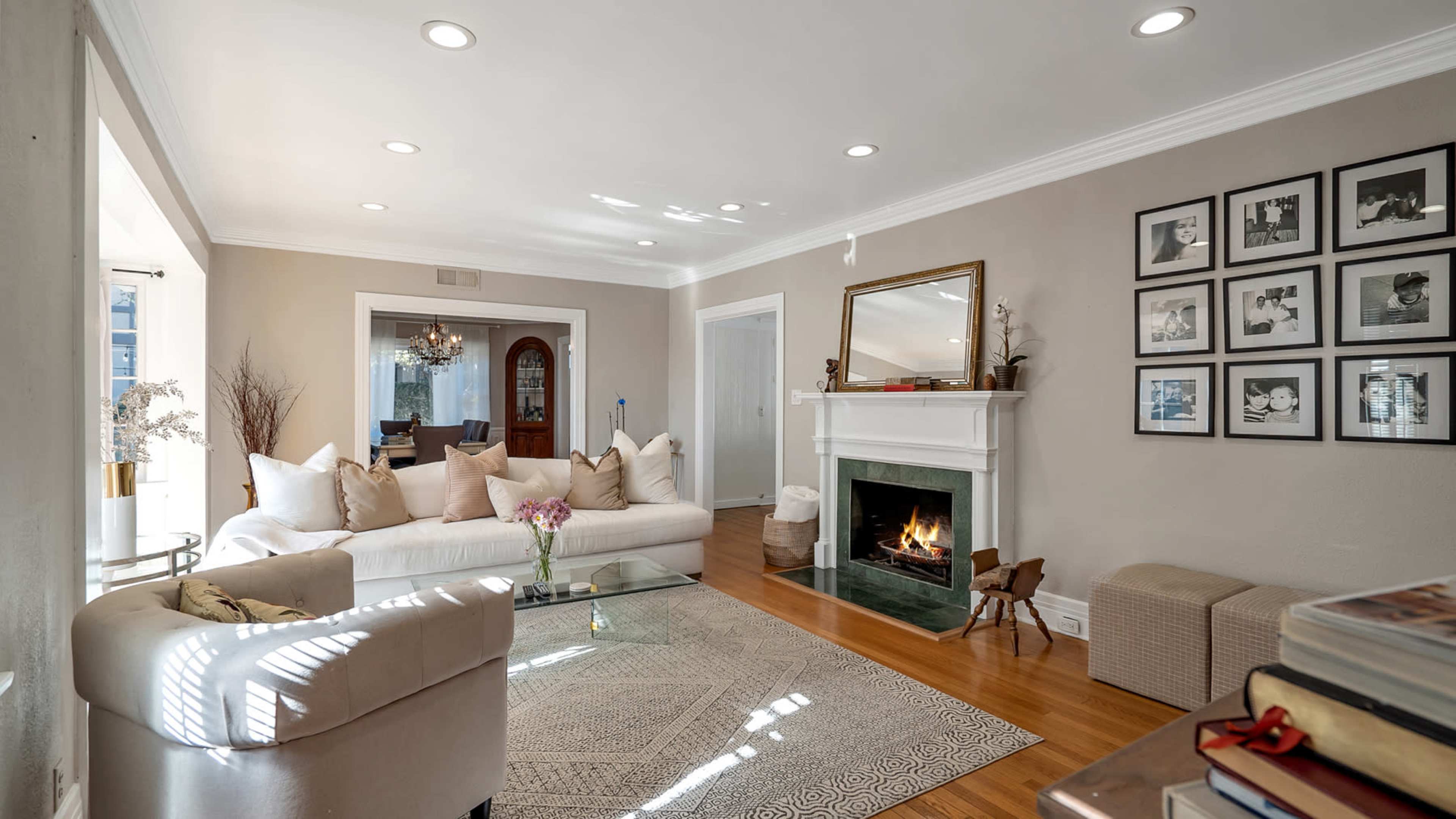 A living room with a white sofa, a fireplace, and a collection of framed black-and-white photographs on the wall.