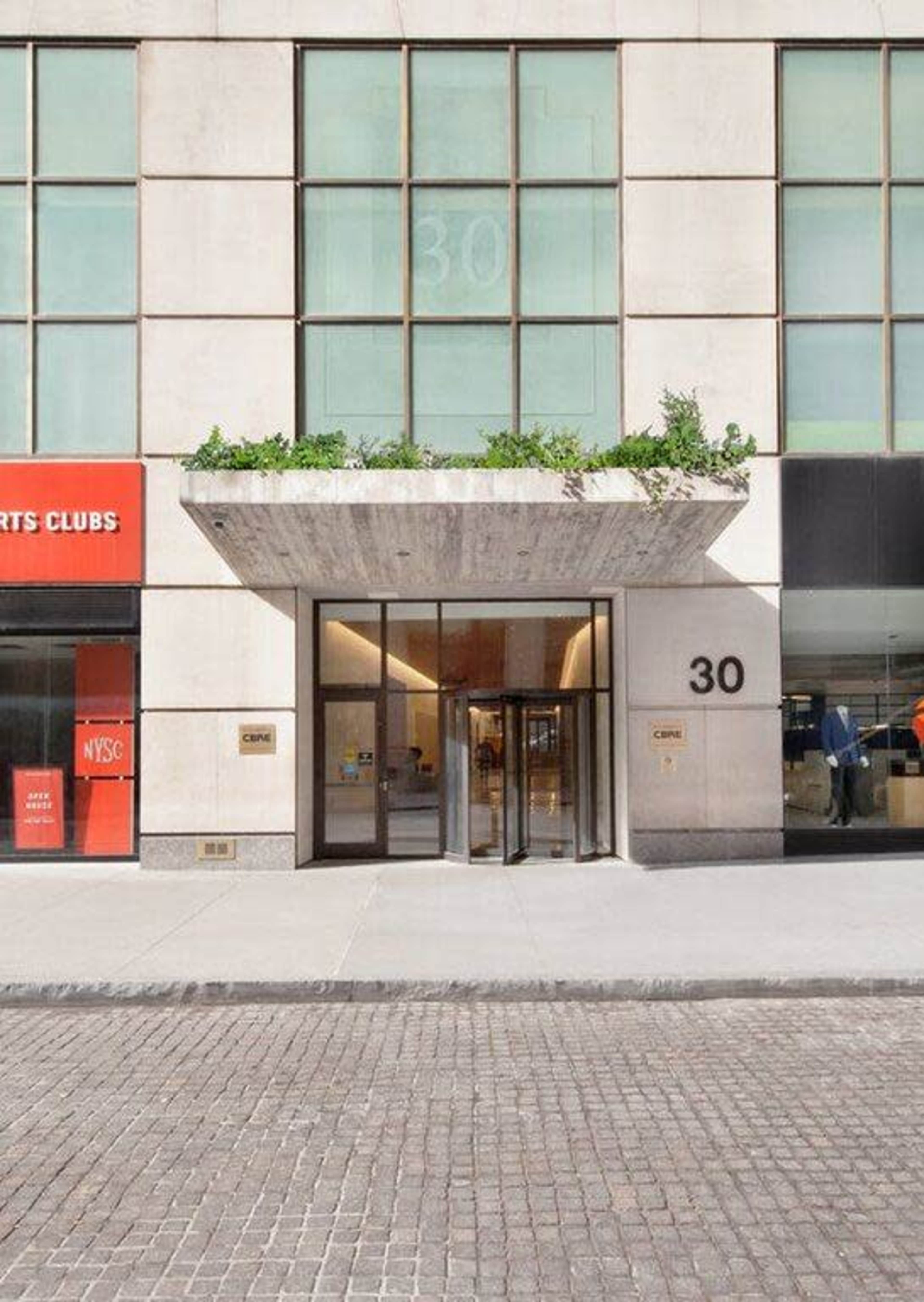 The image shows the entrance of a modern building with a large glass revolving door and a prominent address "30" displayed above.