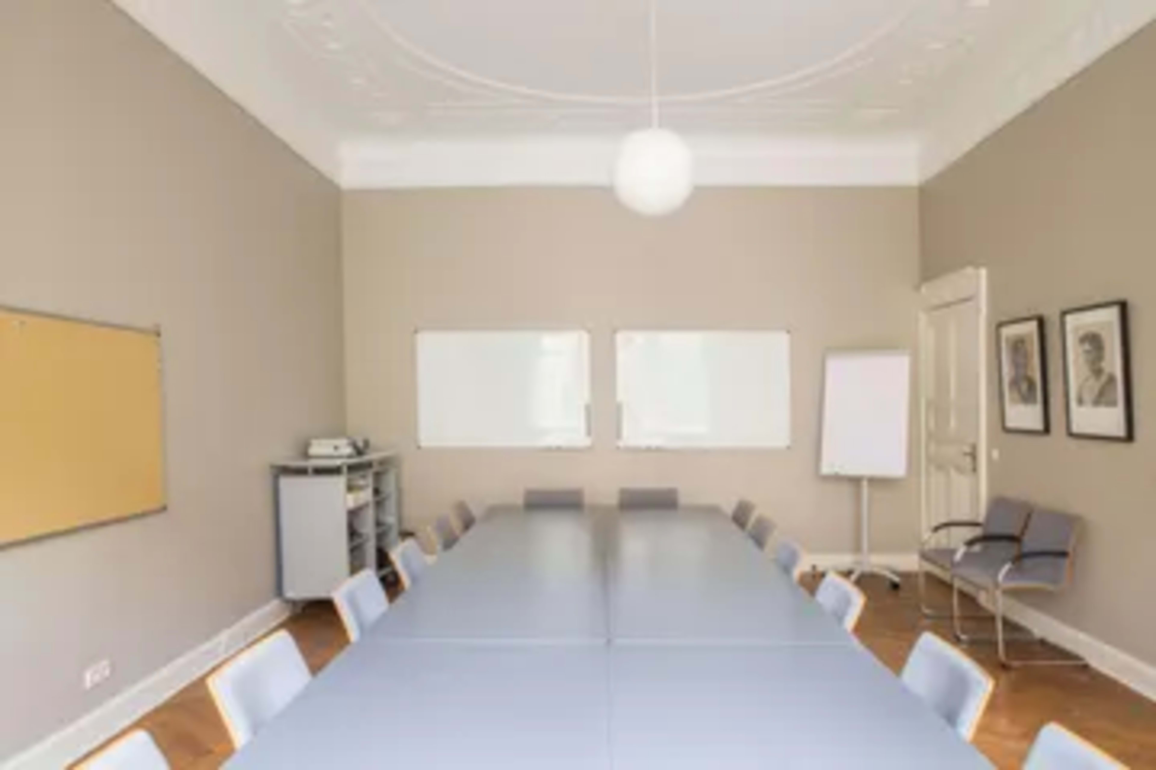 A conference room with a long table, two whiteboards on the wall, and a presentation easel.