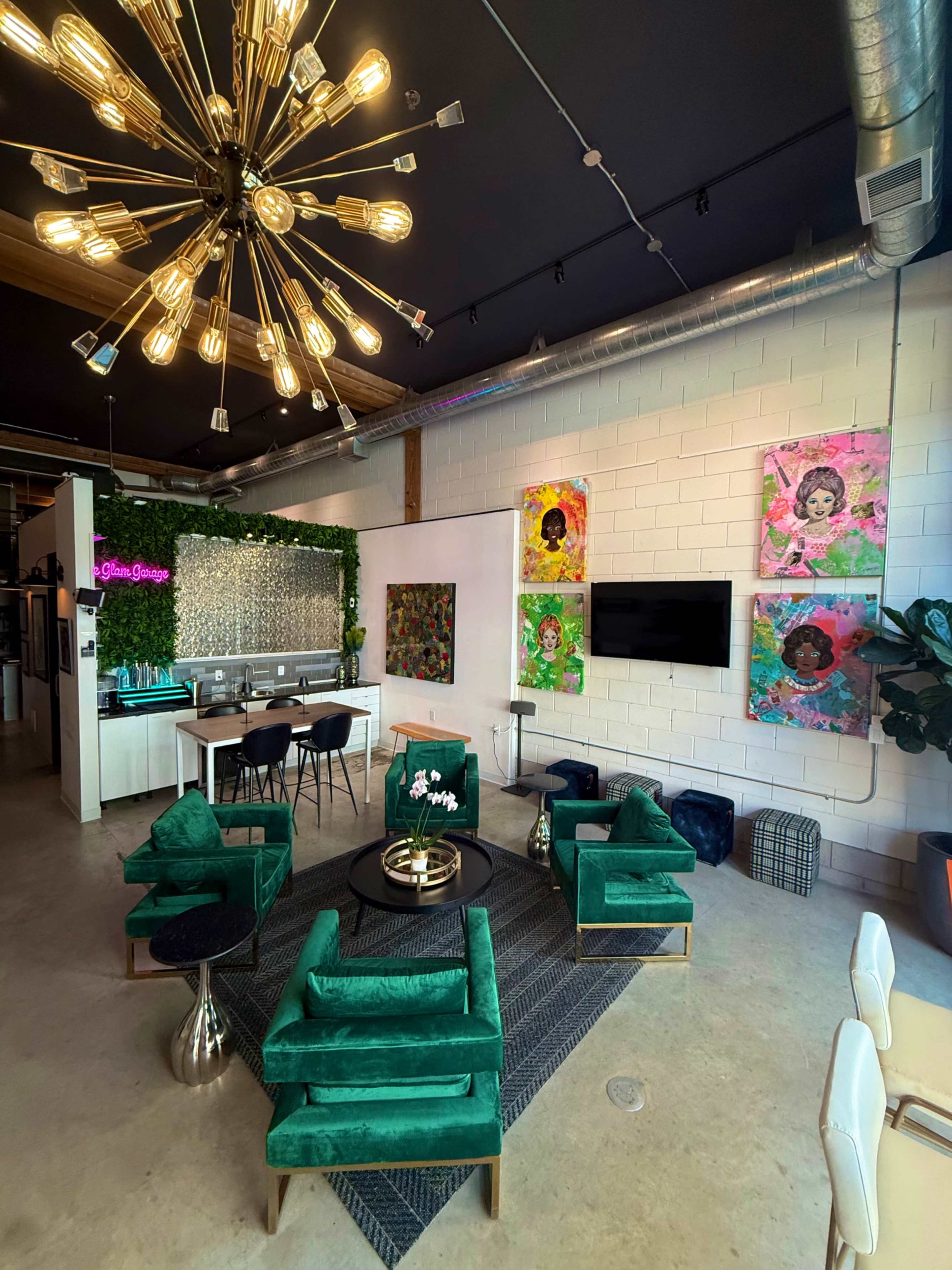 The image shows a modern lounge area featuring green chairs and a black rug, with a bar in the background adorned with plants and colorful artwork on the walls.