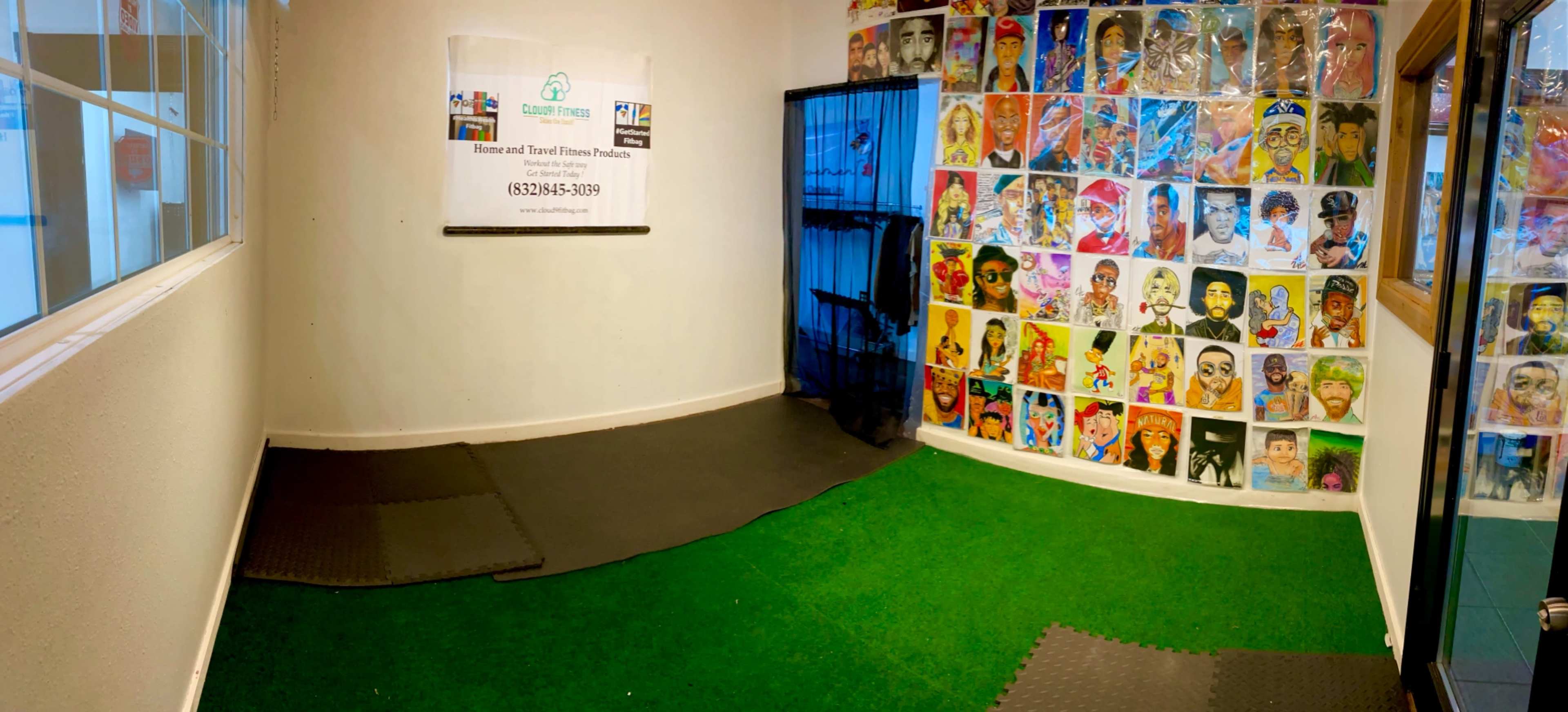 The image shows a room with a green carpet, a black mat area, and a wall covered with colorful portraits, along with a blue curtain and a banner.