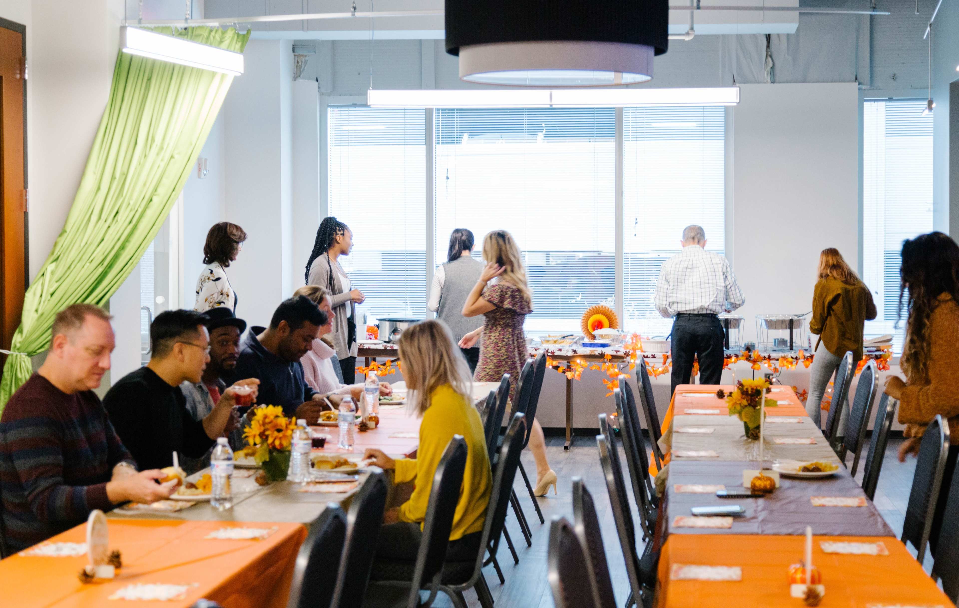 A decorated dining area with several long tables set for a meal, where people are conversing and enjoying food.