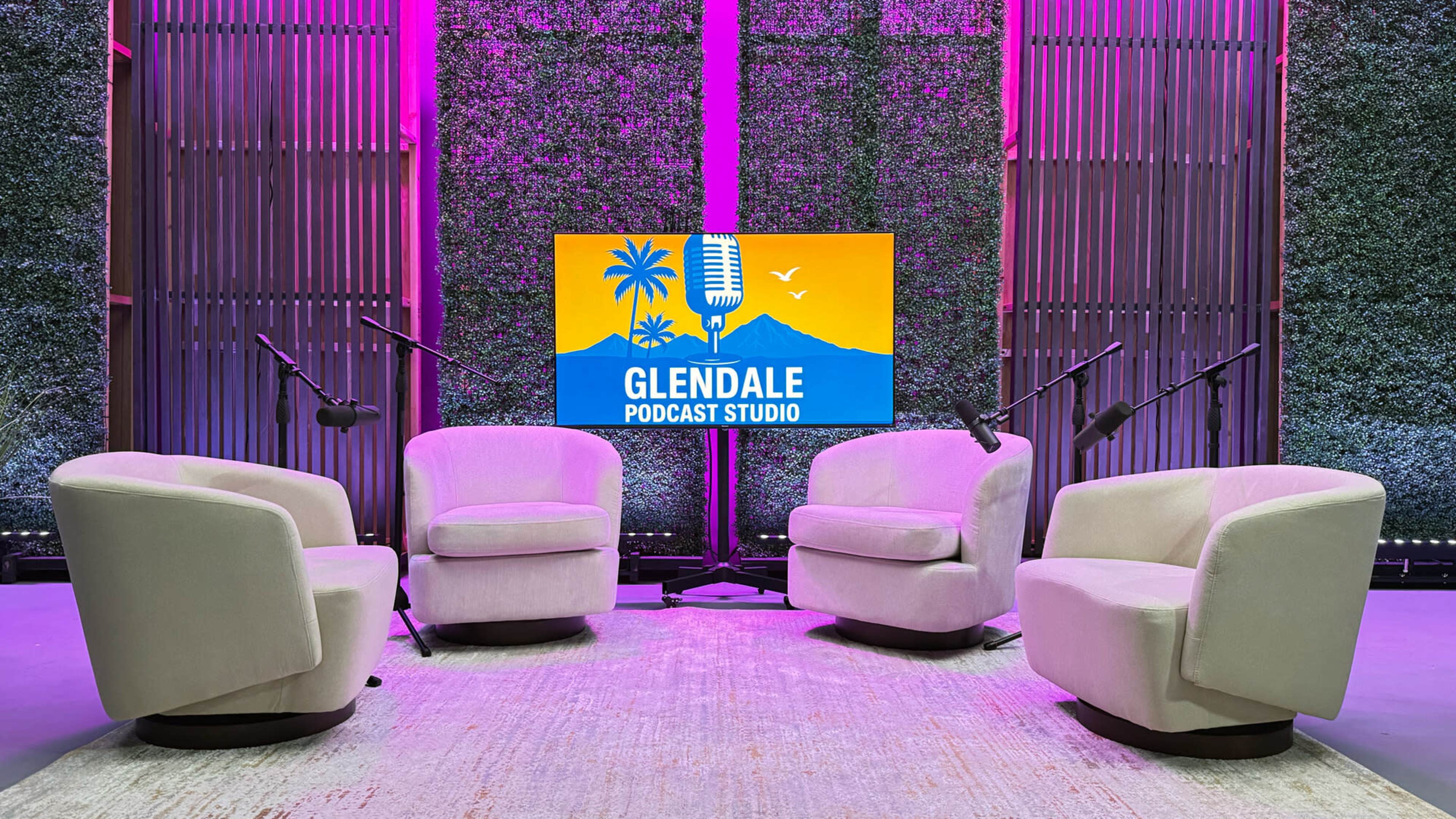 The image shows a podcast studio setup featuring four light-colored chairs arranged around a central television screen displaying the "Glendale Podcast Studio" logo against a backdrop of greenery.