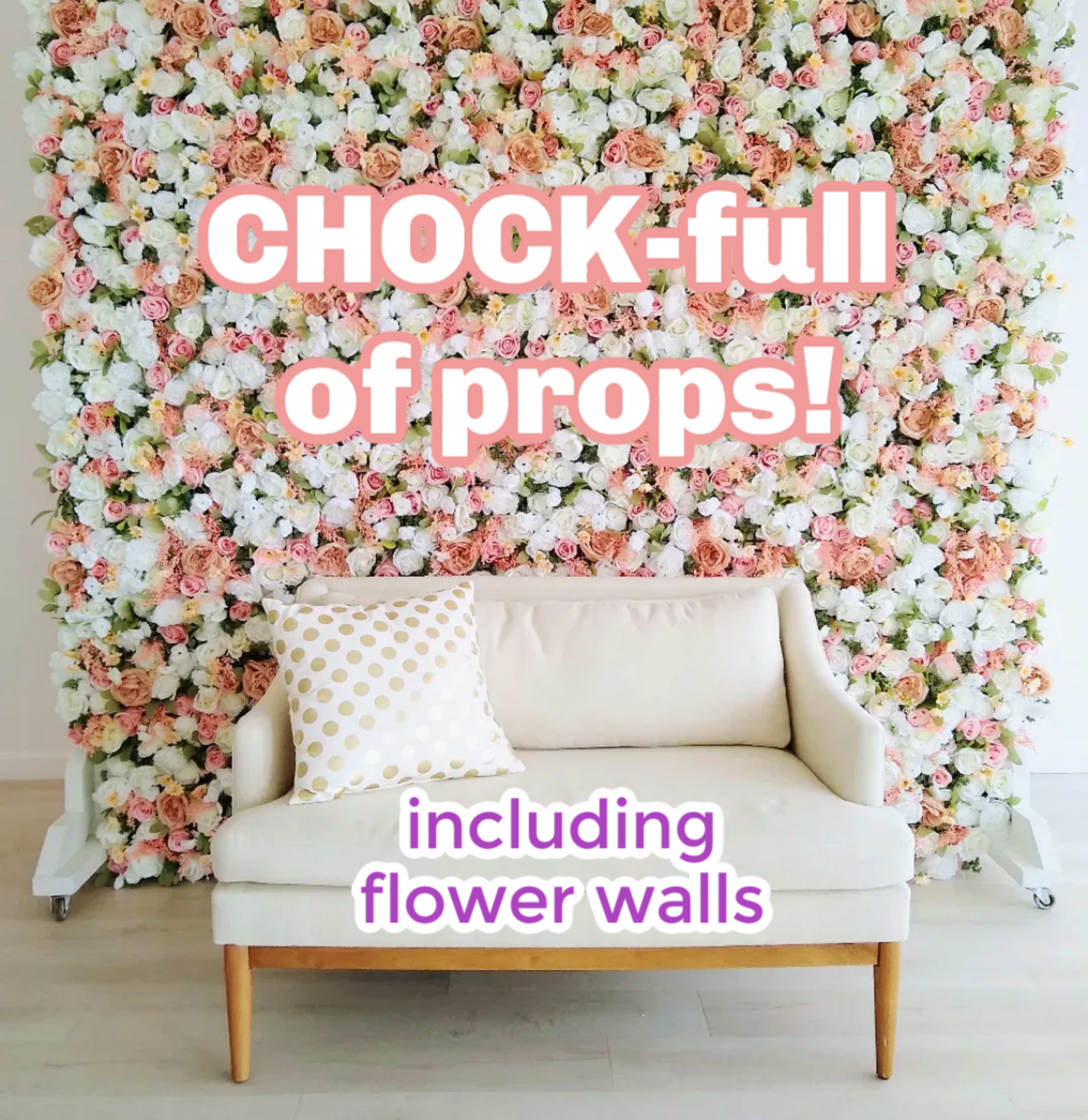 A white sofa sits in front of a floral wall adorned with pink and white flowers.