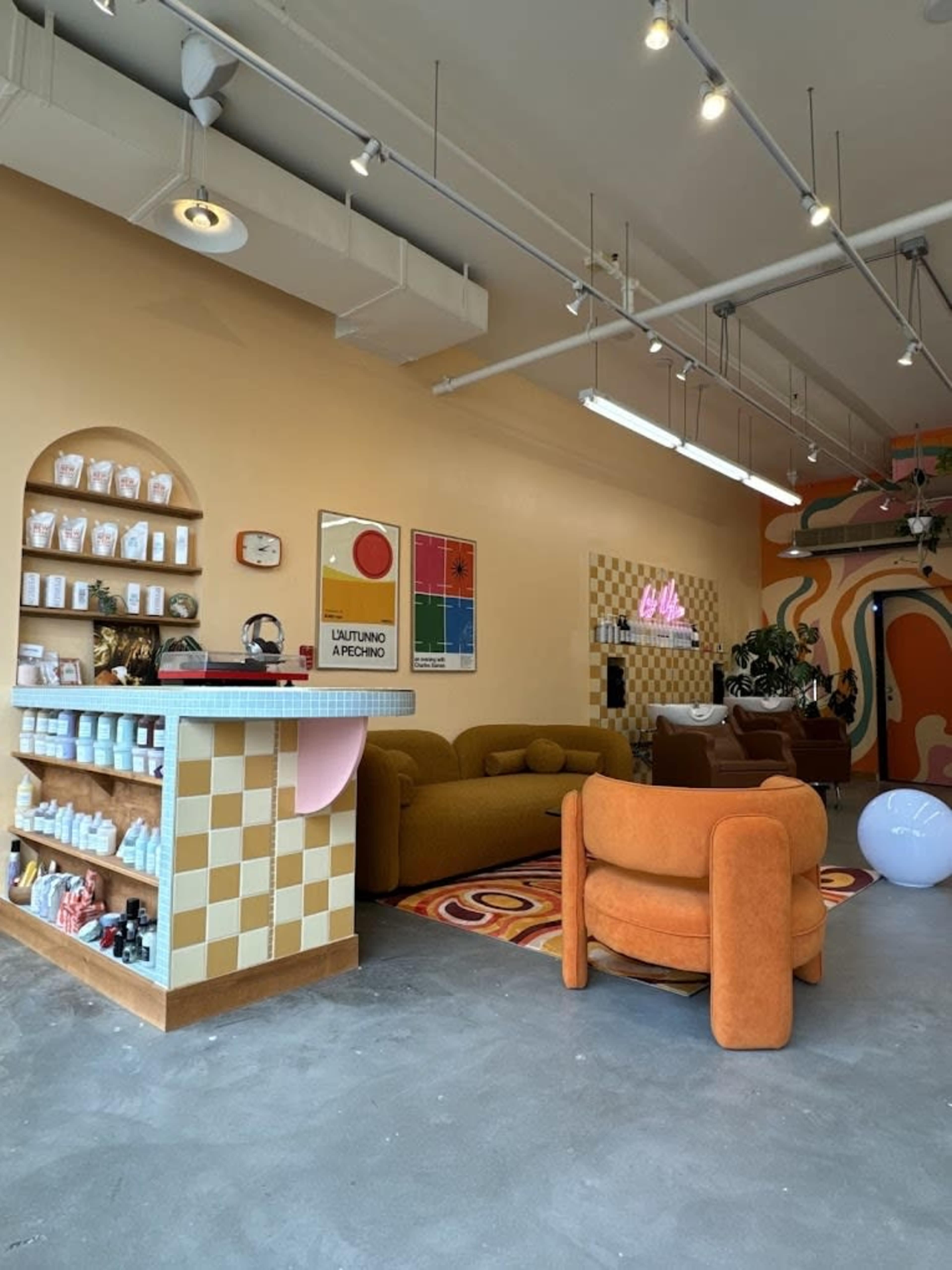 A modern interior of a bright, cozy café featuring retro-style furniture, a checkered counter, and colorful wall art.