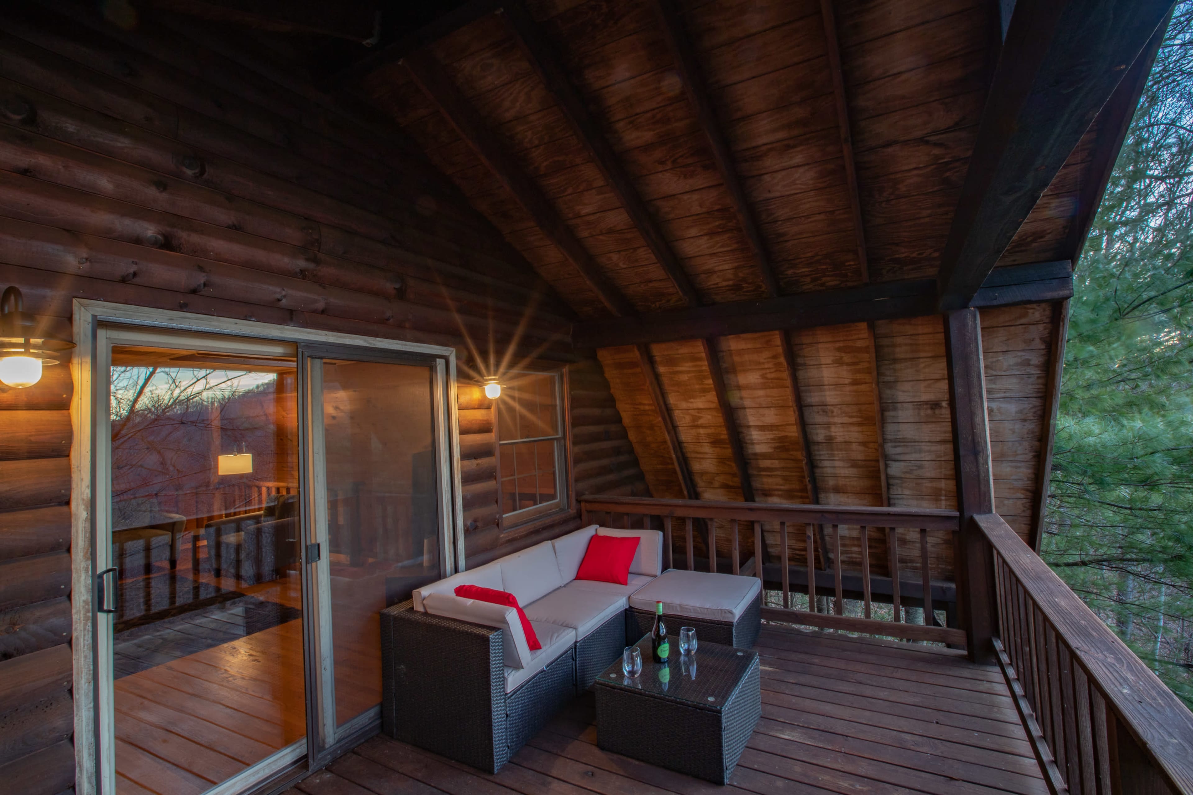 A wooden balcony with a seating area featuring a couch and small table, overlooking a scenic landscape.