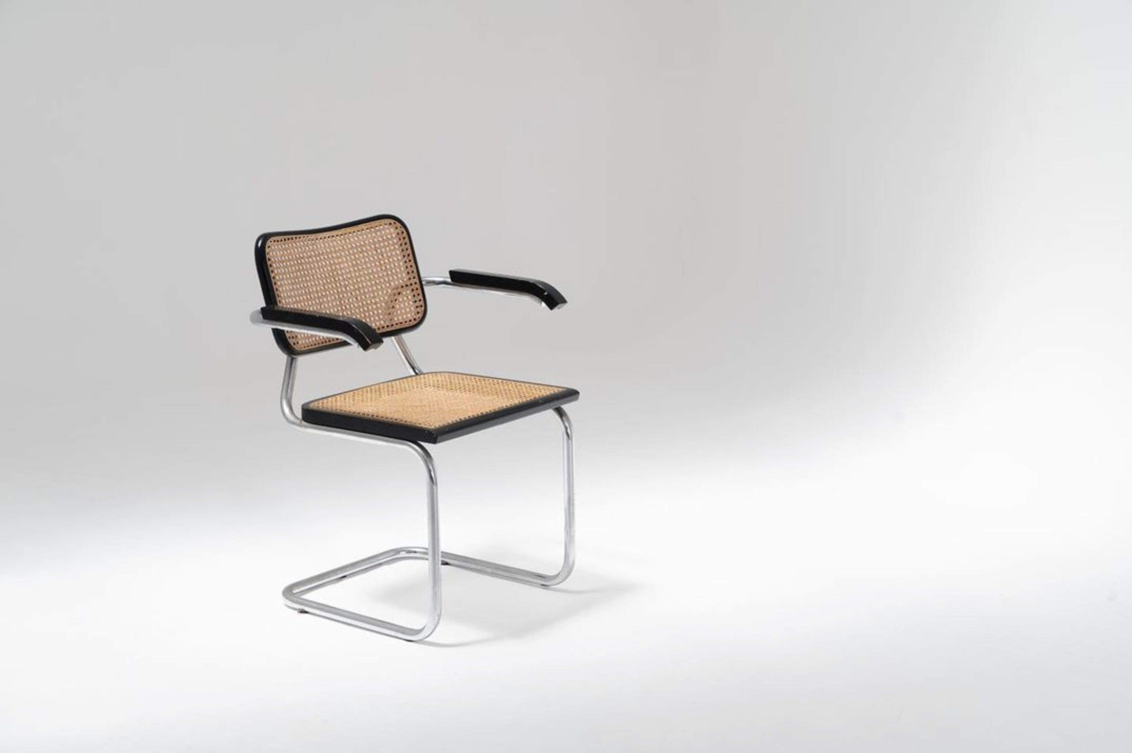 A modern chair with a metal frame, cane seat, and armrests.