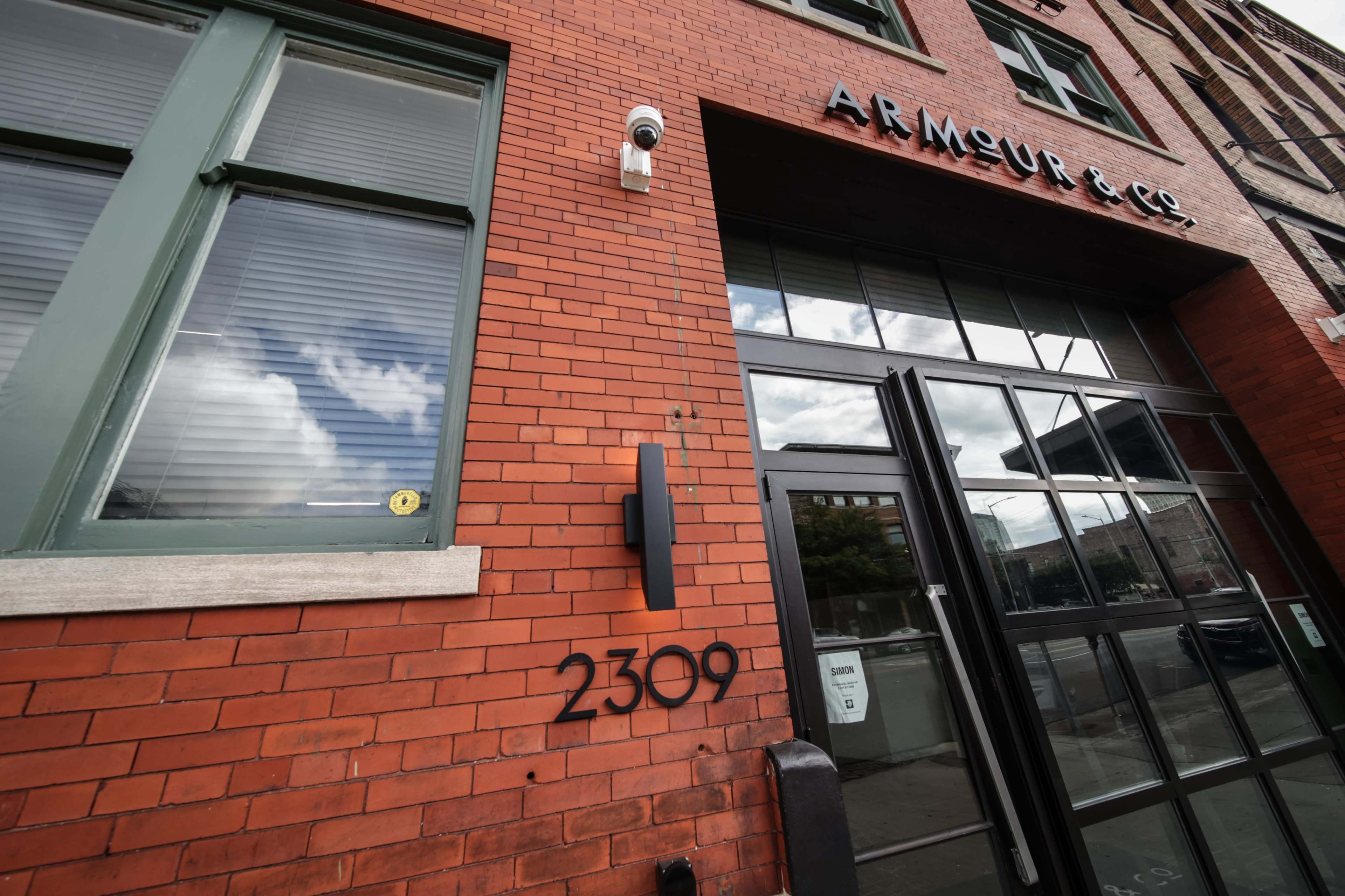 The image features a brick building with the name "Armour & Co." displayed above a large entrance, along with a street number "2309" prominently shown on the wall.