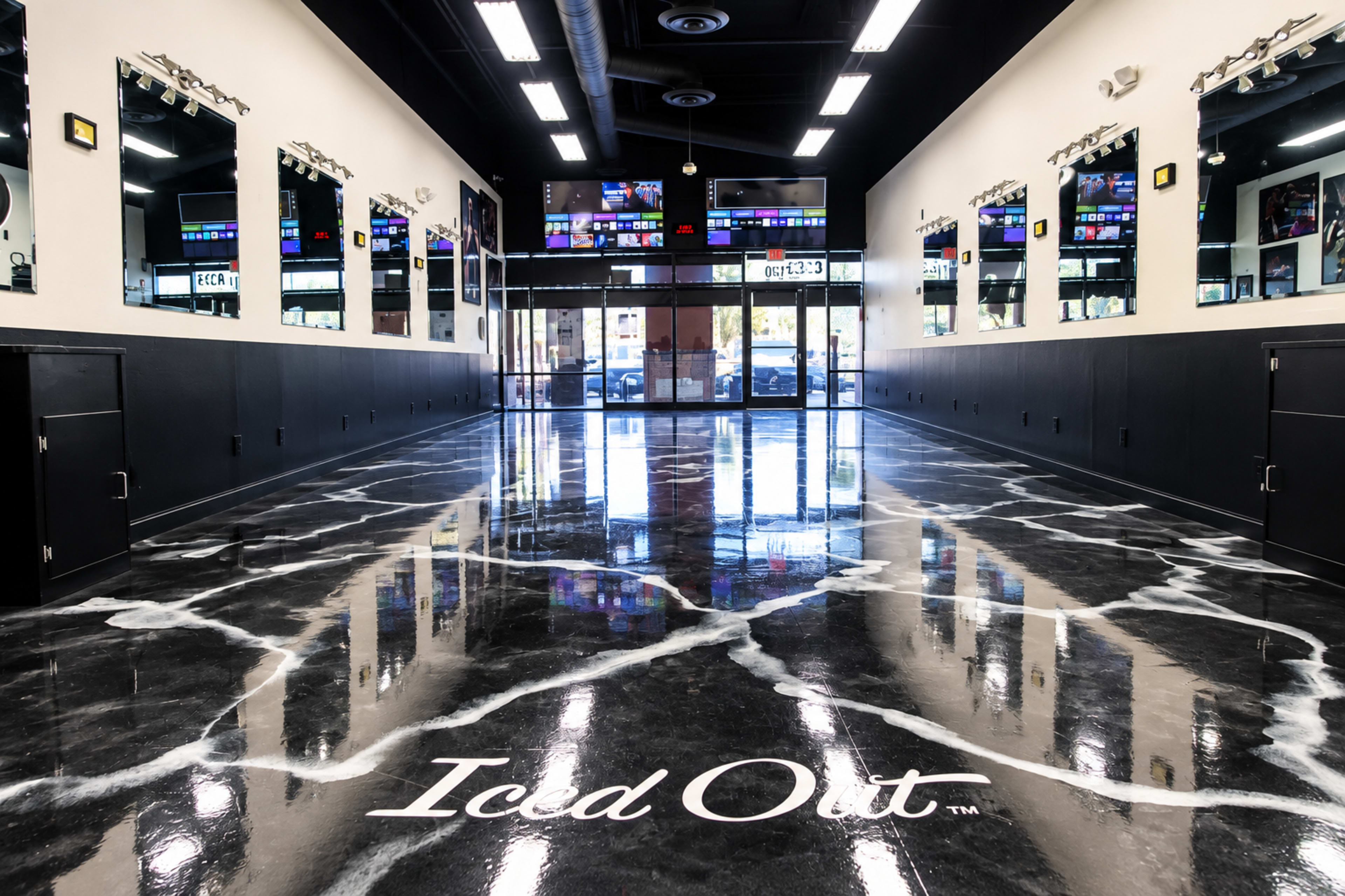 The image shows a modern interior of a store called "Iced Out," featuring a sleek, marbled floor and numerous mirrors along the walls.