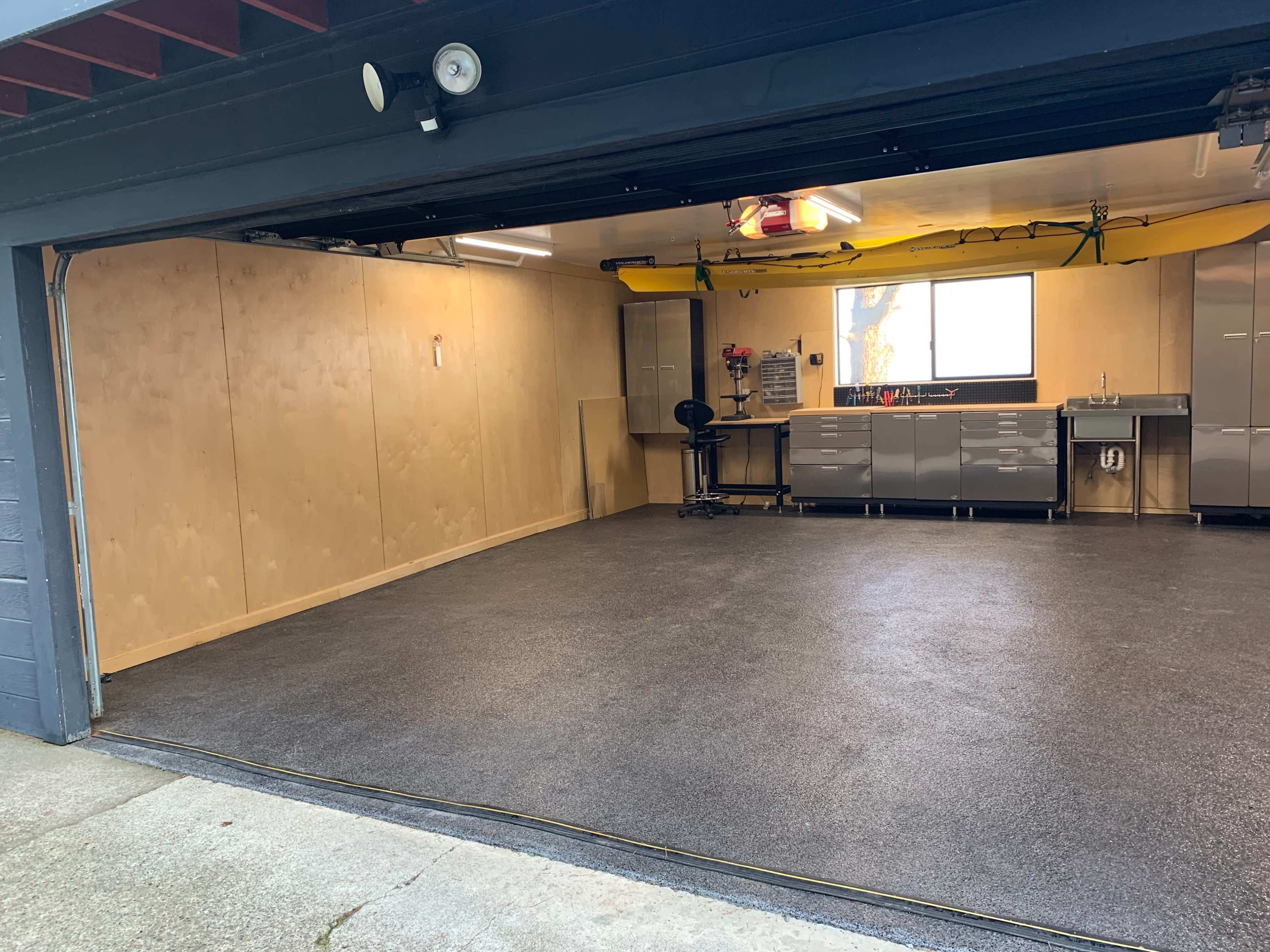 A clean garage with a polished floor, wooden paneling, and organized workstations along the walls.