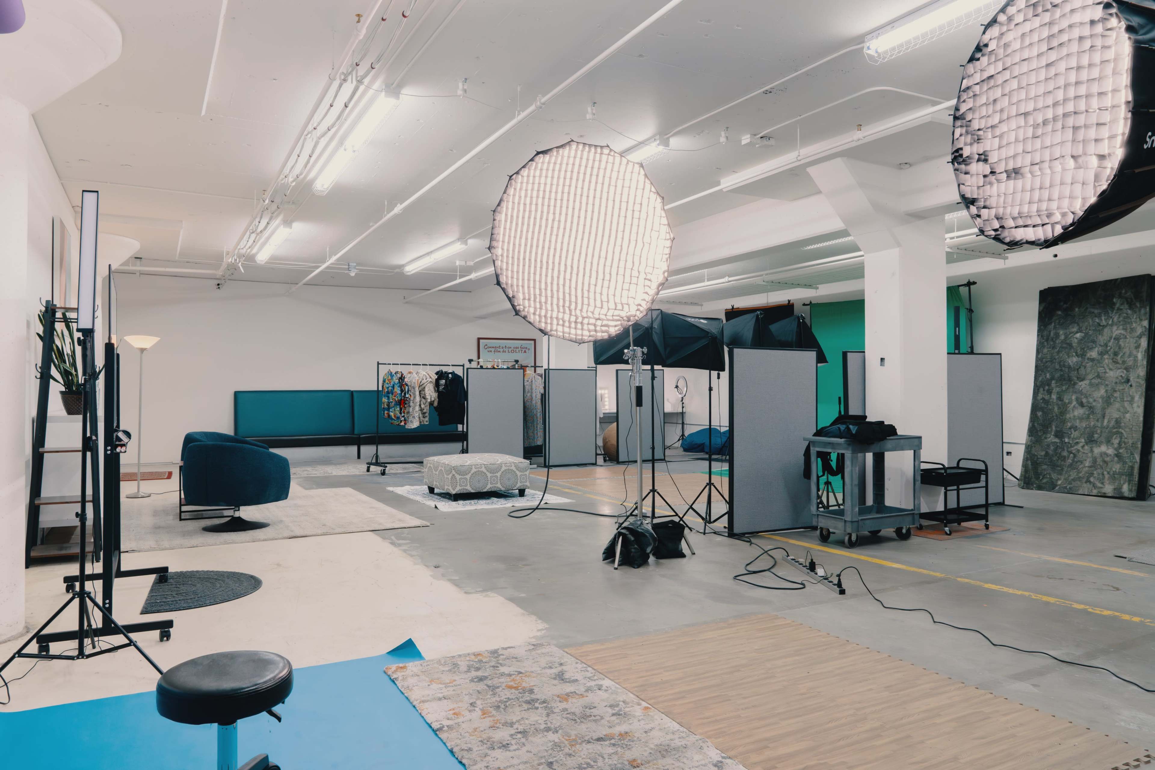 The image shows a spacious photography studio equipped with softbox lights, backdrops, and various props arranged for a photo shoot.