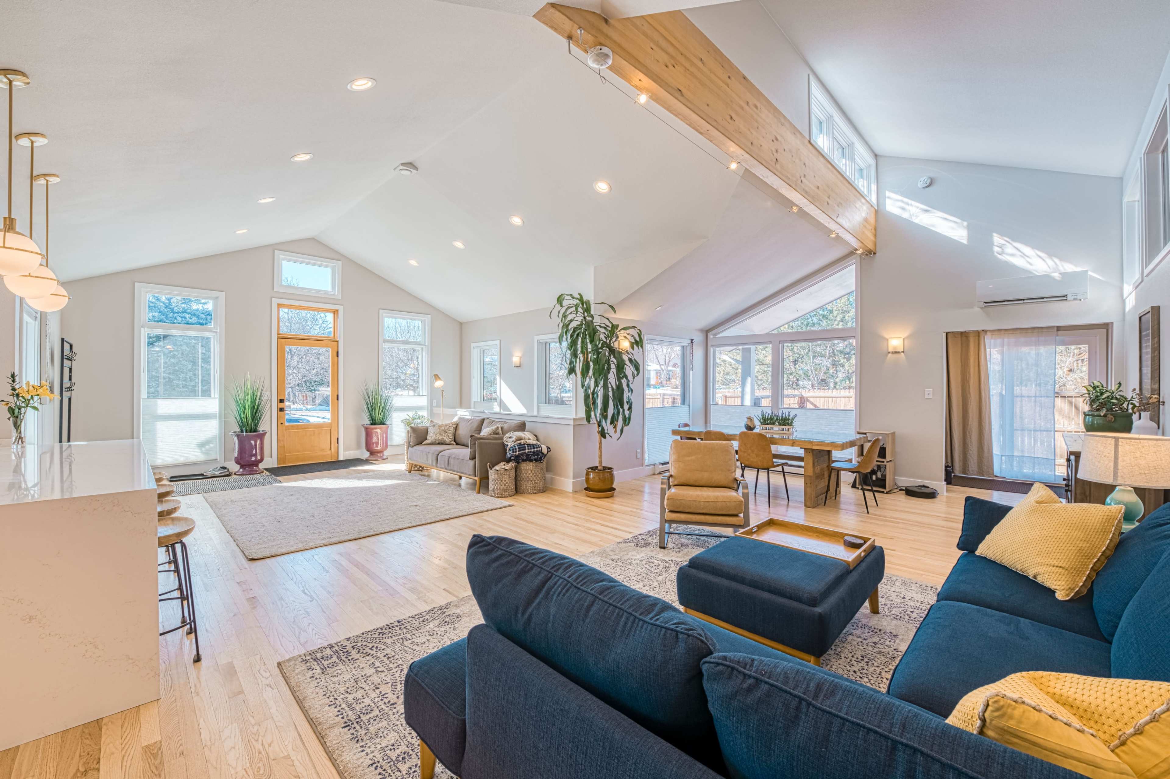 A spacious living room with high ceilings, large windows, and comfortable seating arranged around a coffee table.
