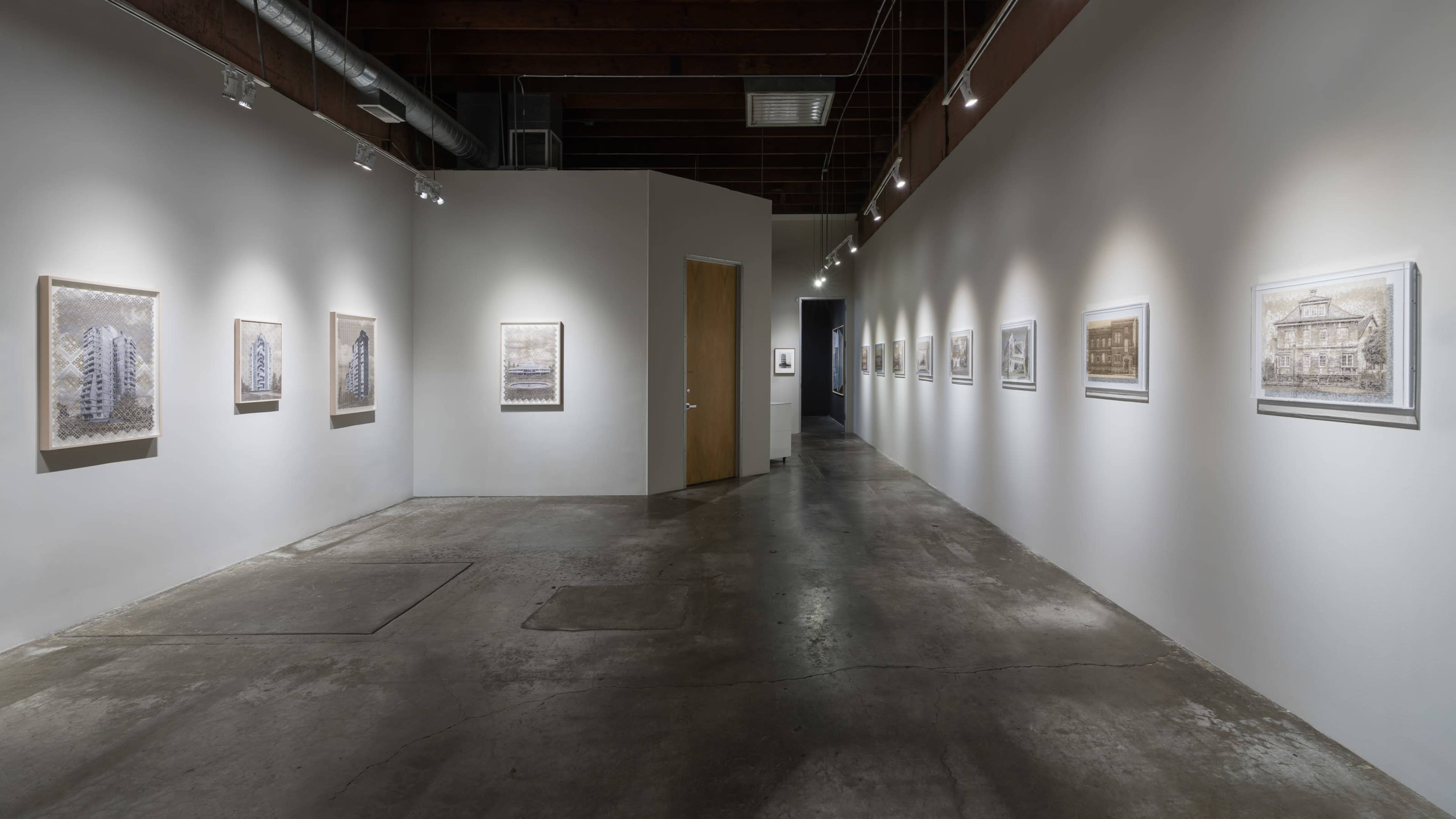A modern art gallery with framed artworks displayed along the walls and a doorway leading to another area.