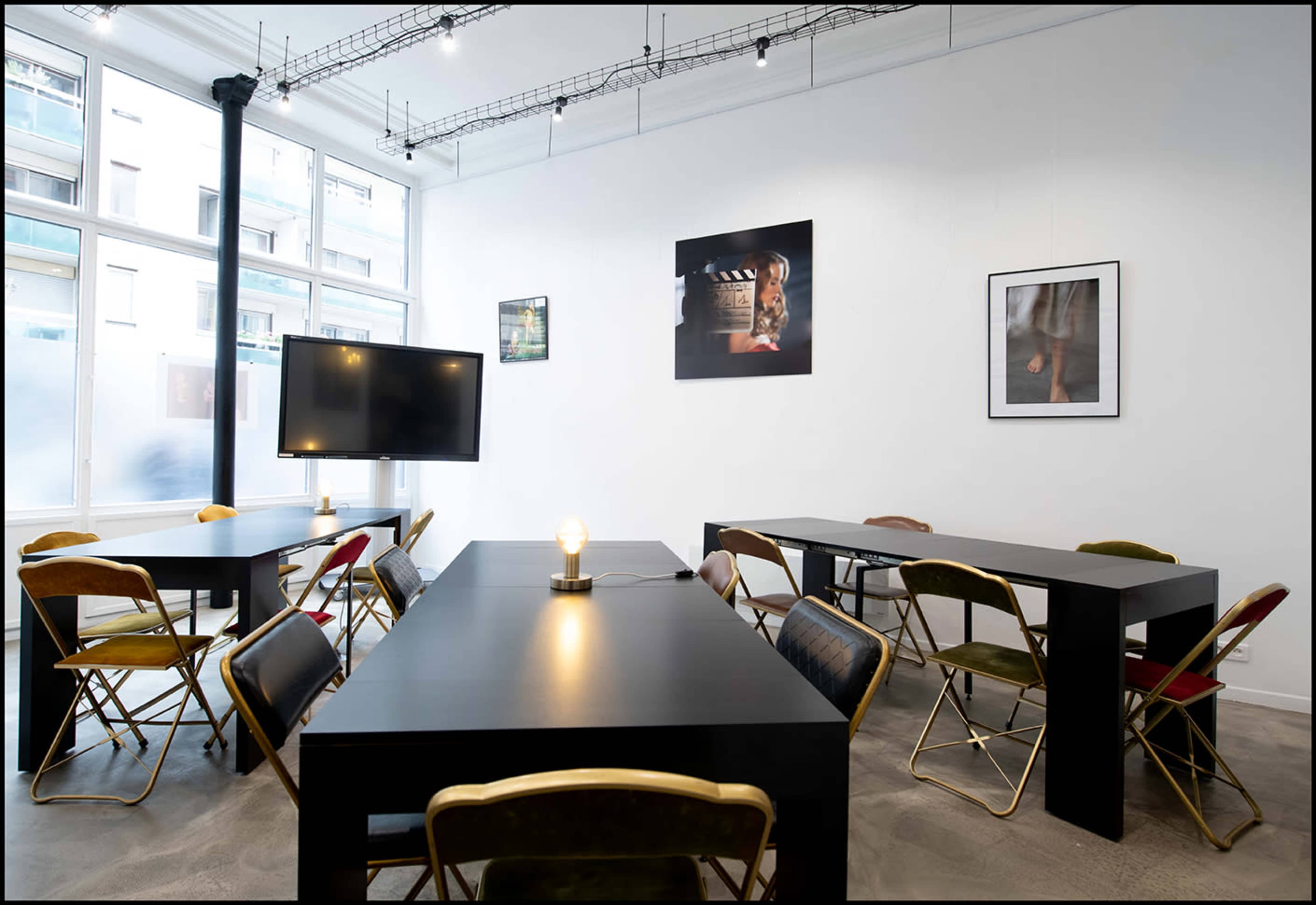 A modern meeting room with several black tables and multi-colored chairs arranged around the space.