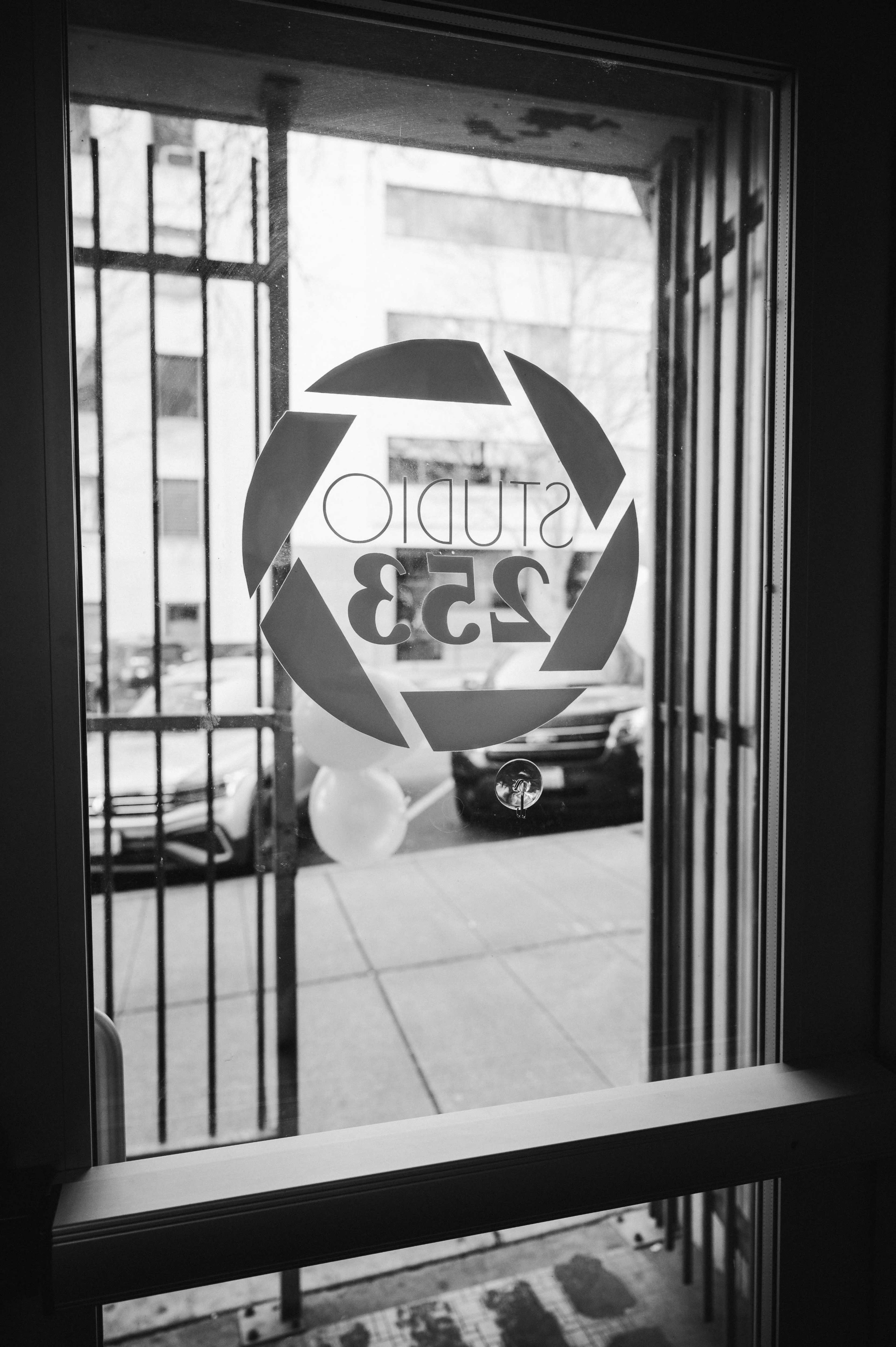 A glass door displays a logo for "Studio 253," with a view of parked cars outside.