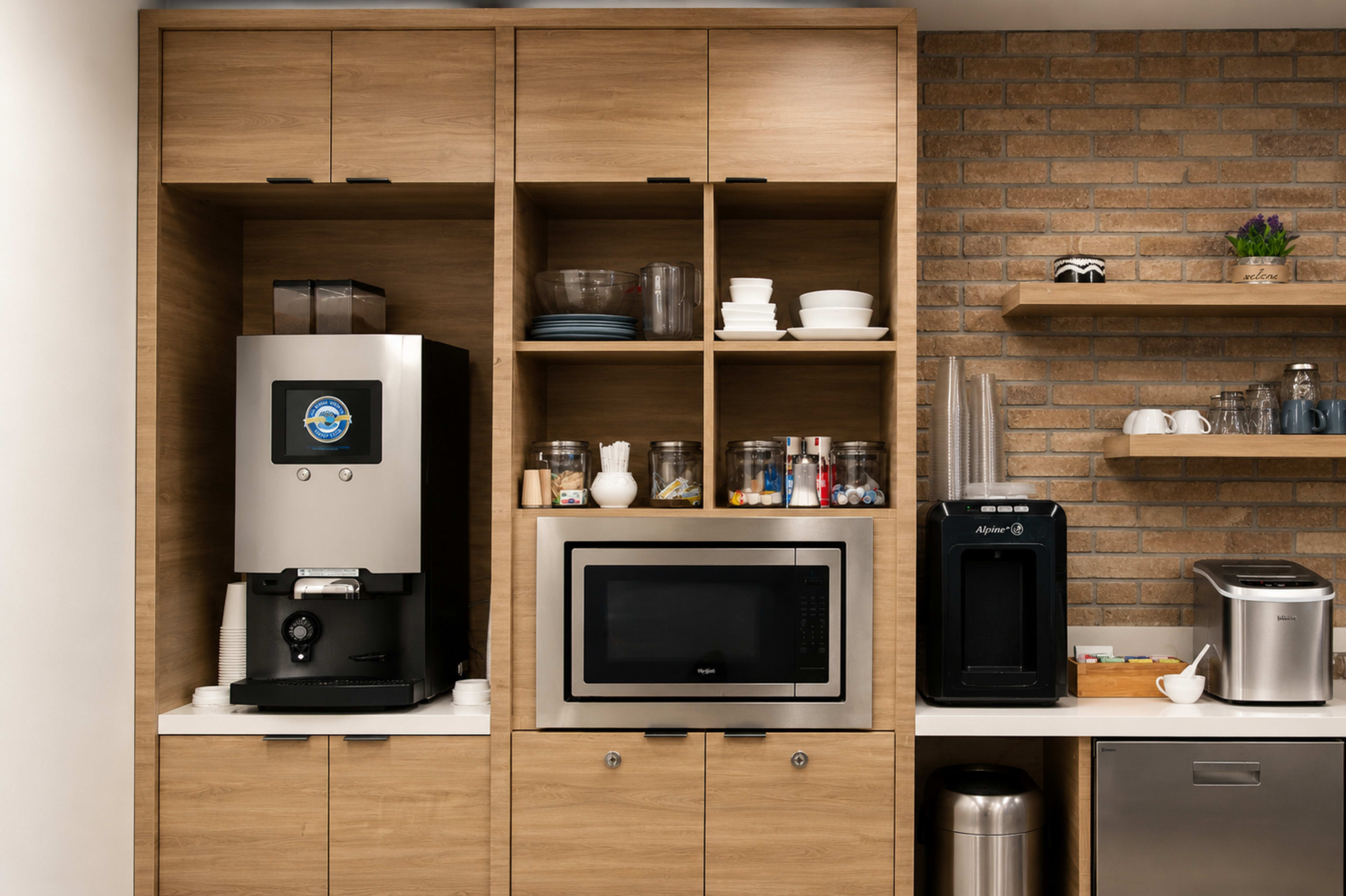 The image shows a modern kitchen corner featuring a coffee machine, a microwave, and various kitchenware arranged on wooden shelves.