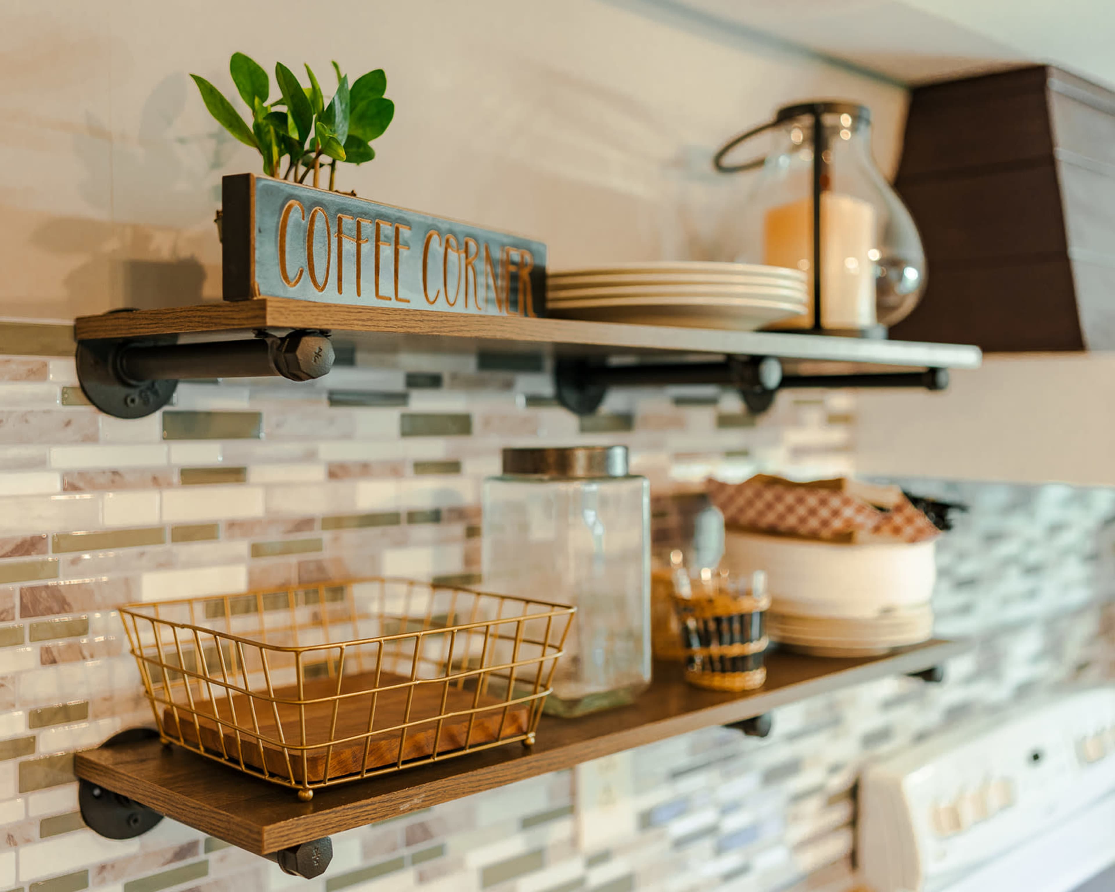 Wooden shelves in a kitchen with decorative items, including a coffee-themed sign, a plant, and various containers arranged neatly.