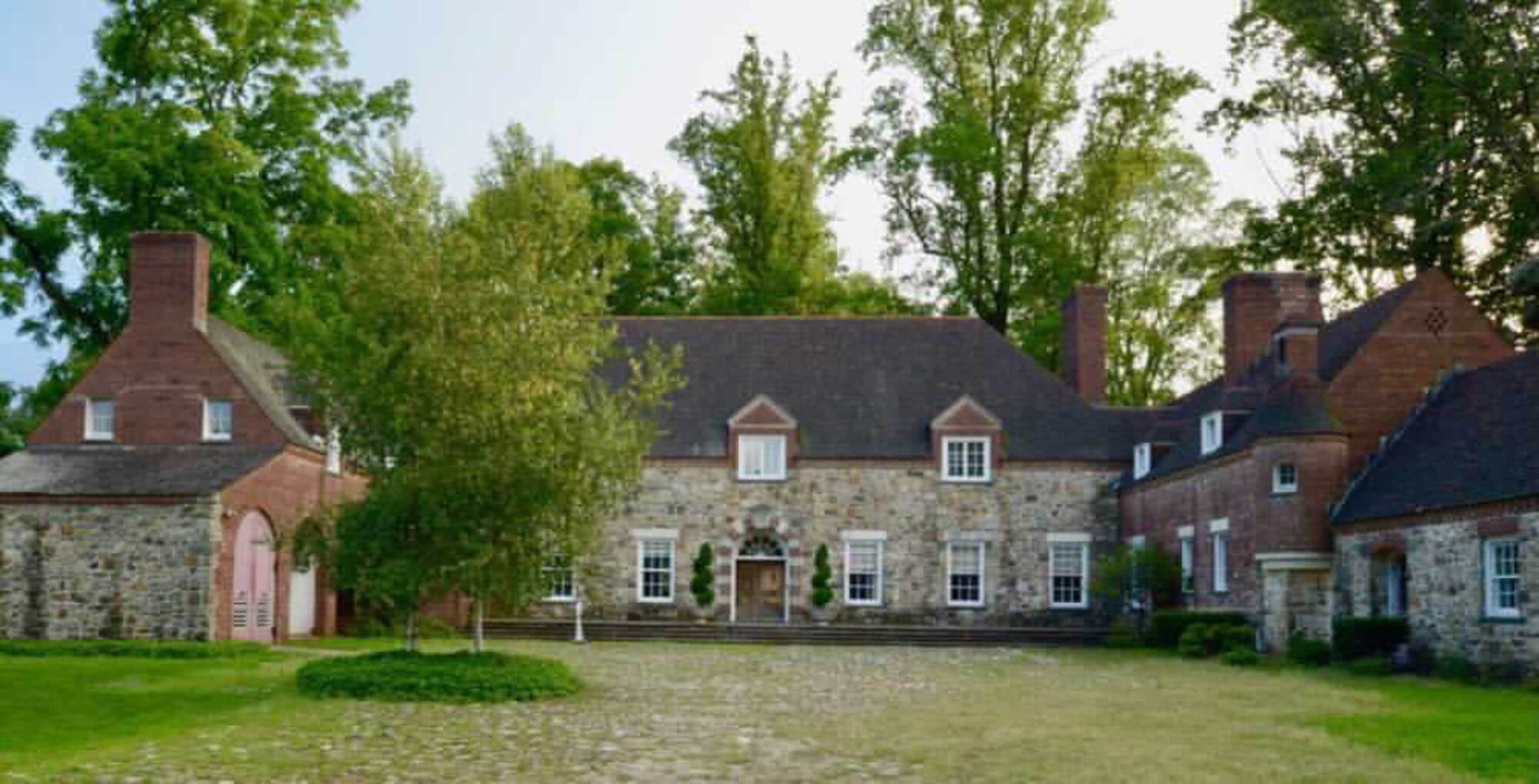 A large stone and brick house surrounded by trees and a grassy area.